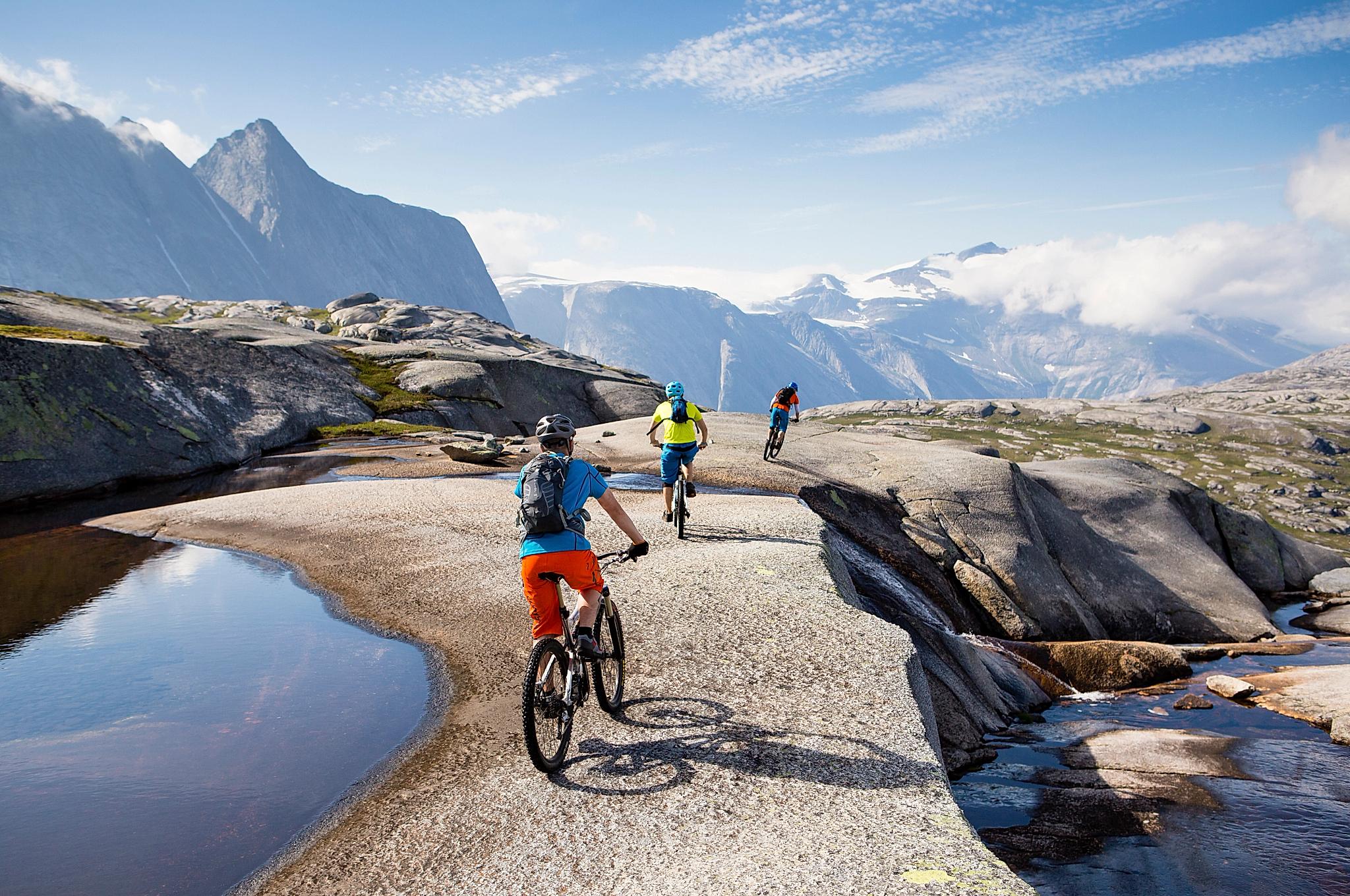 Three people mountain biking in Narvik in Northern Norway, surrounded by tall mountains