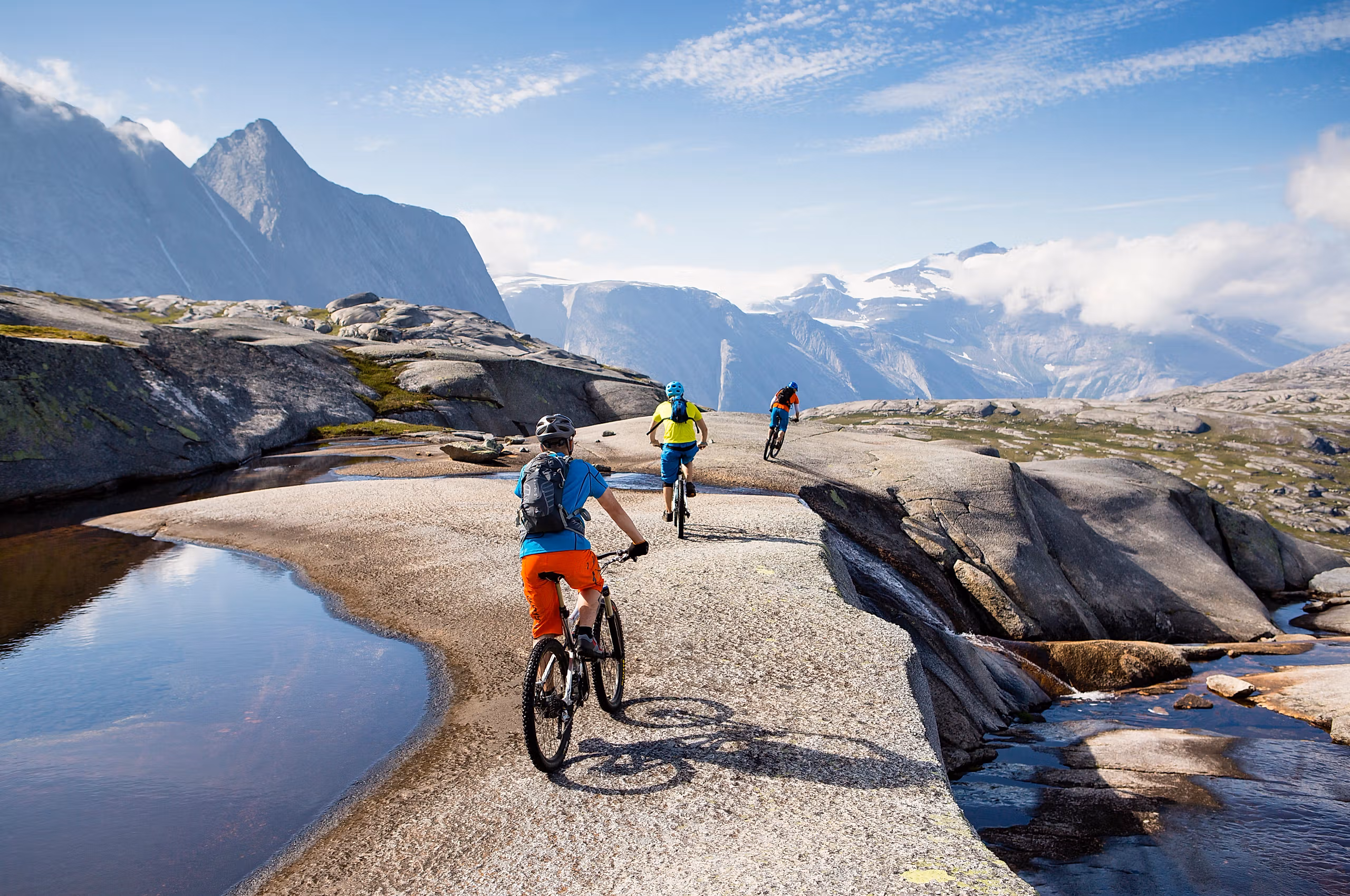 Three people mountain biking in Narvik in Northern Norway, surrounded by tall mountains
