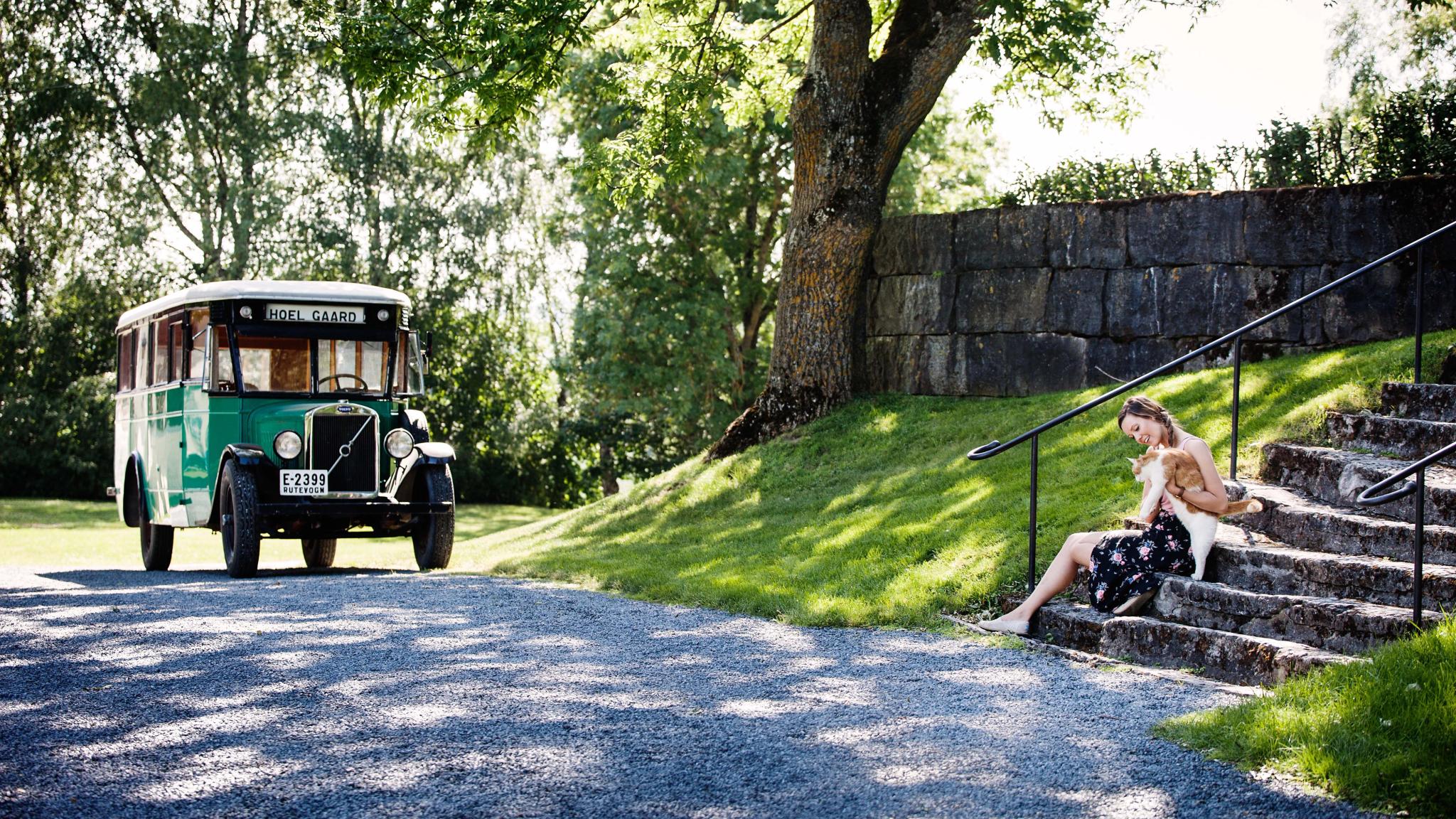 En dame sitter med en katt i fanget utenfor Hoel Gård på Nes-halvøya i Ringsaker, Østlandet