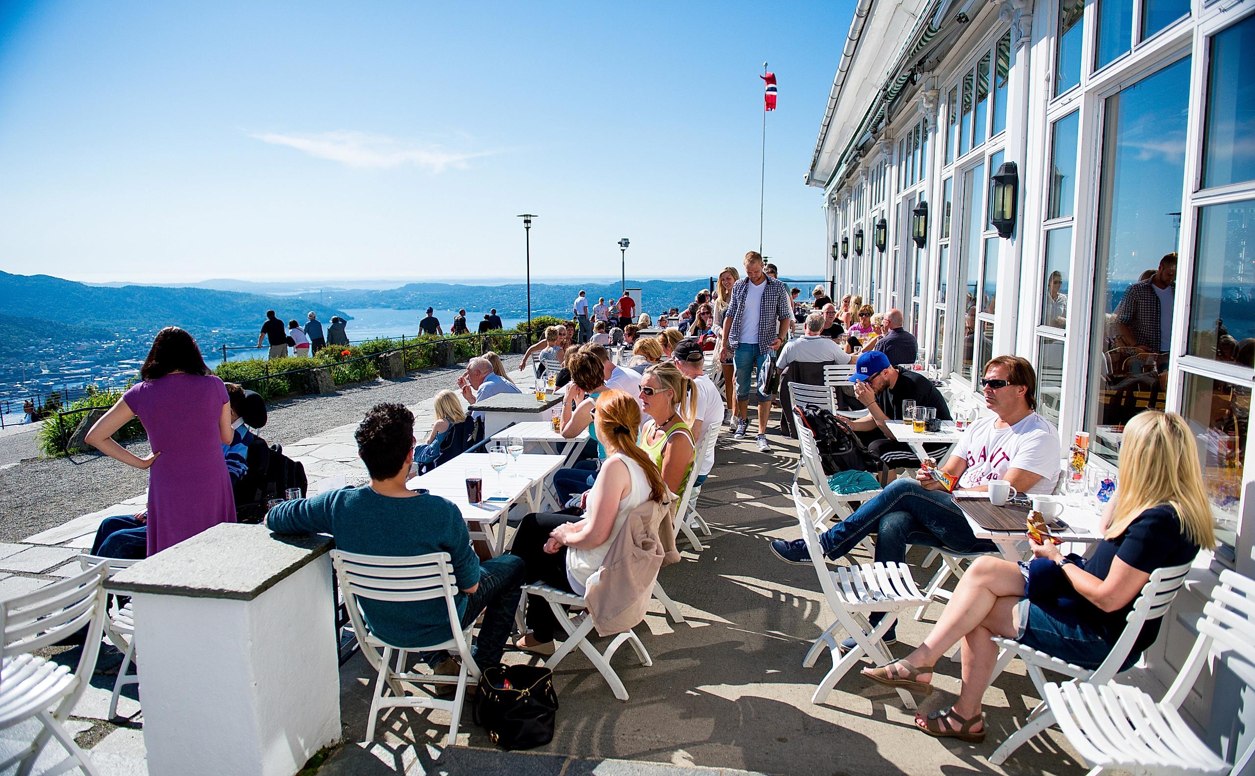 A group of people enjoying the view over Bergen from the restaurant at the Fløyen mountain in Norway