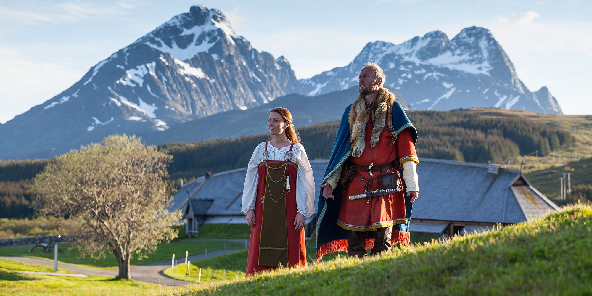 To vikinger står foran høvdingshuset på Lofotr Vikingmuseum i Lofoten