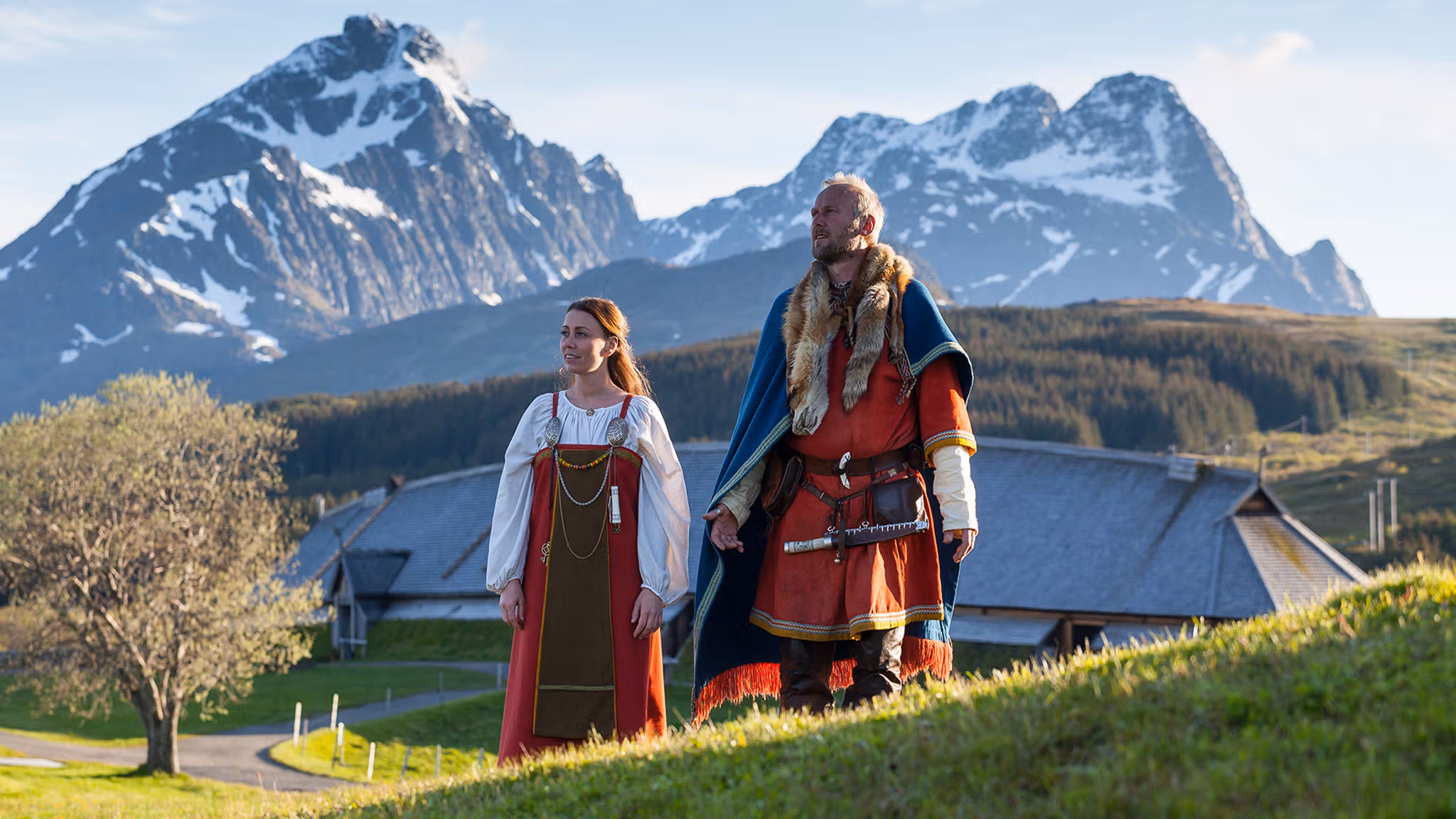 To vikinger står foran høvdingshuset på Lofotr Vikingmuseum i Lofoten