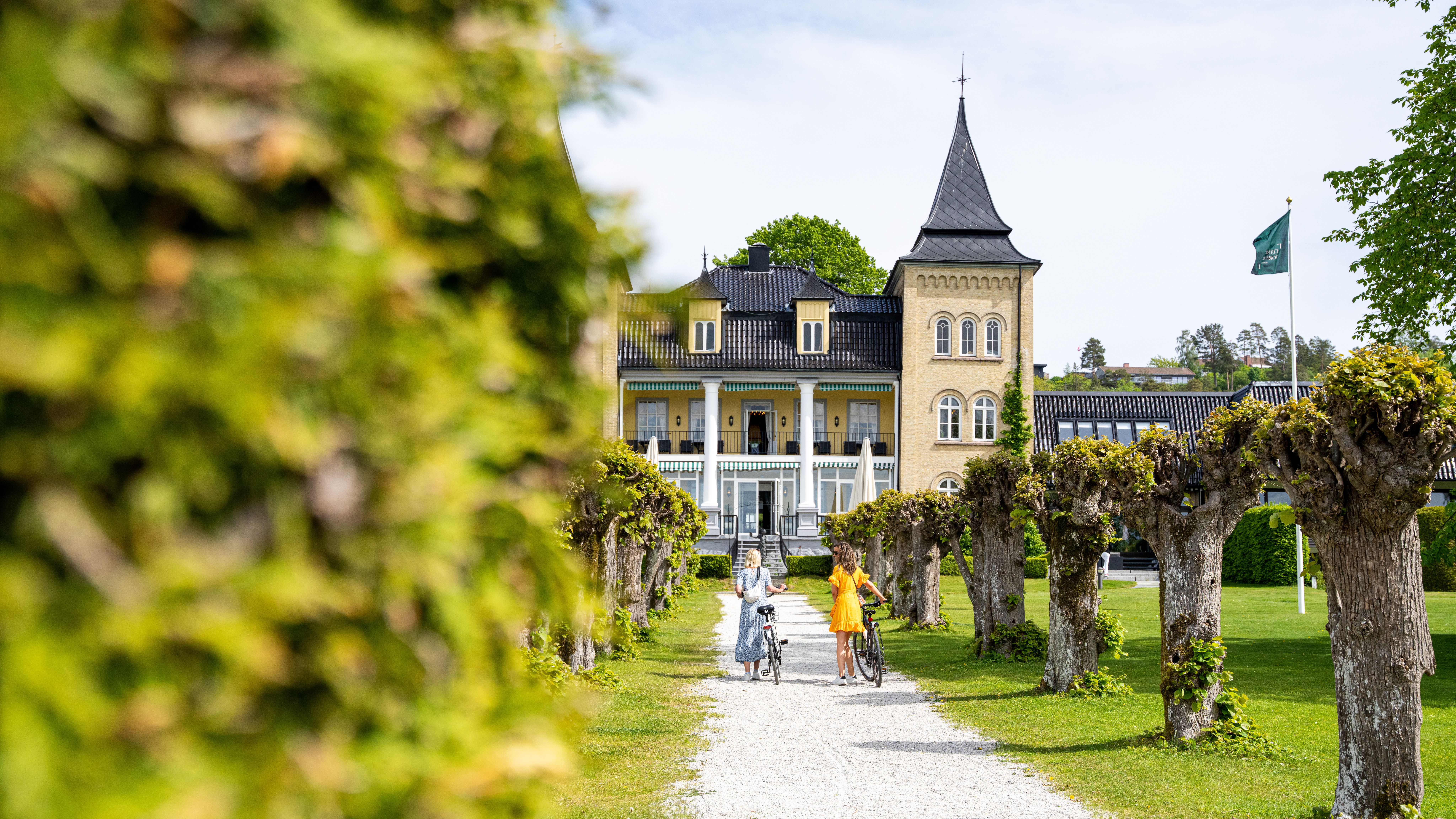 To kvinner med sykkel går foran Resnes Gods på Jeløy i Moss