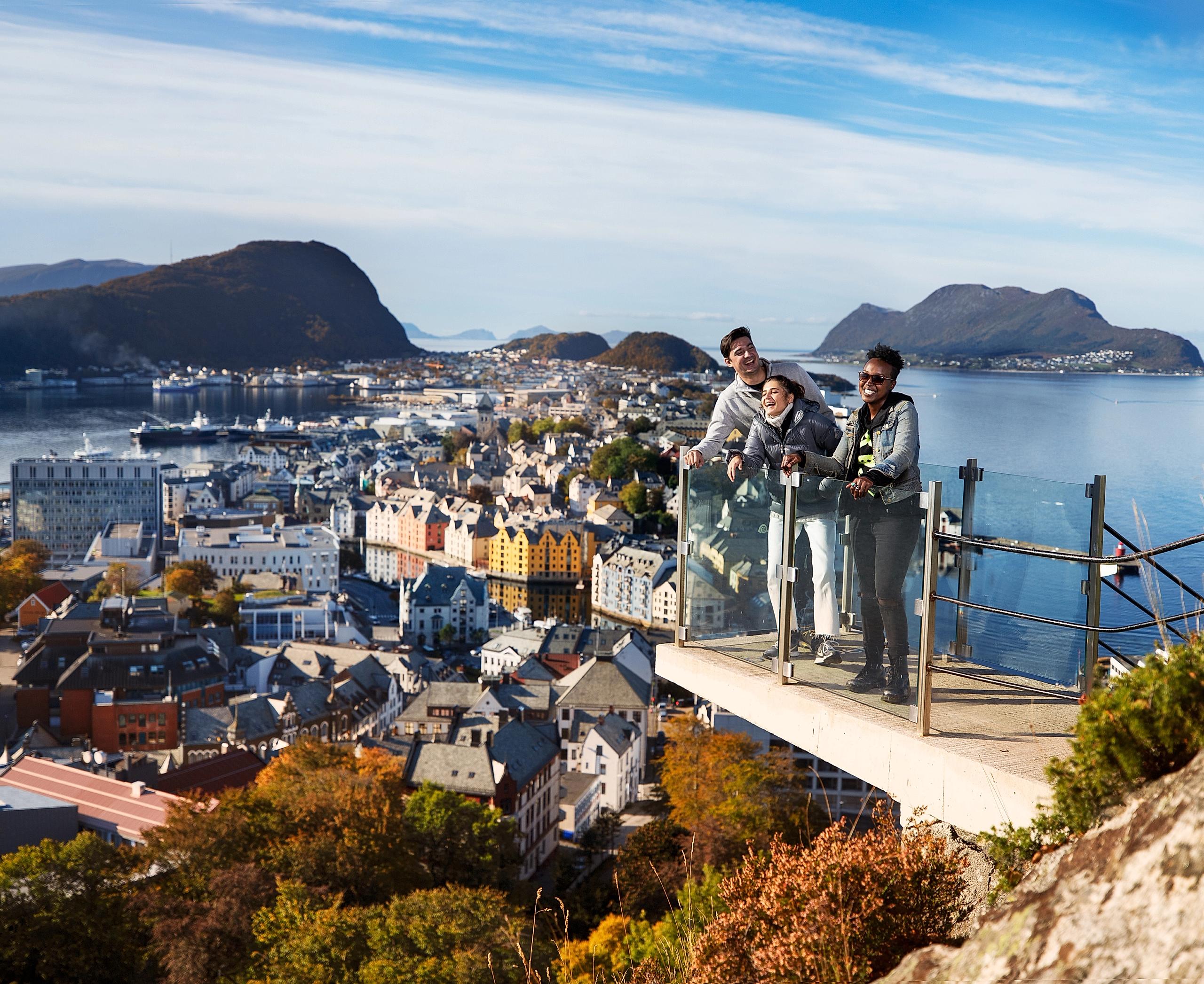 Tres personas disfrutan las vistas desde el mirador panorámico en lo alto del monte Aksla, en Ålesund, la Noruega de los fiordos.