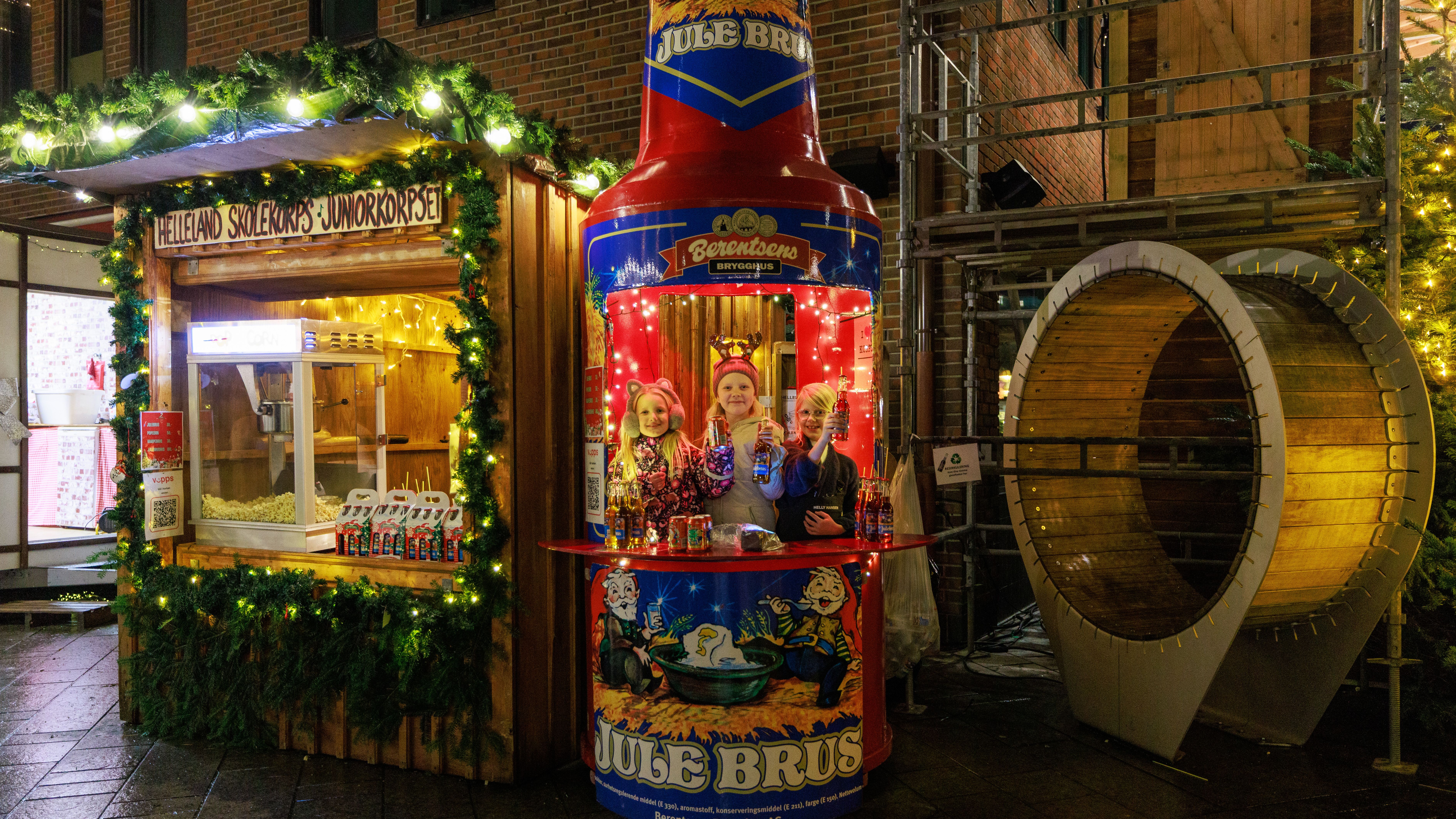 Three young girls inside a Christmas soda shaped stall at Egersund Christmas market 