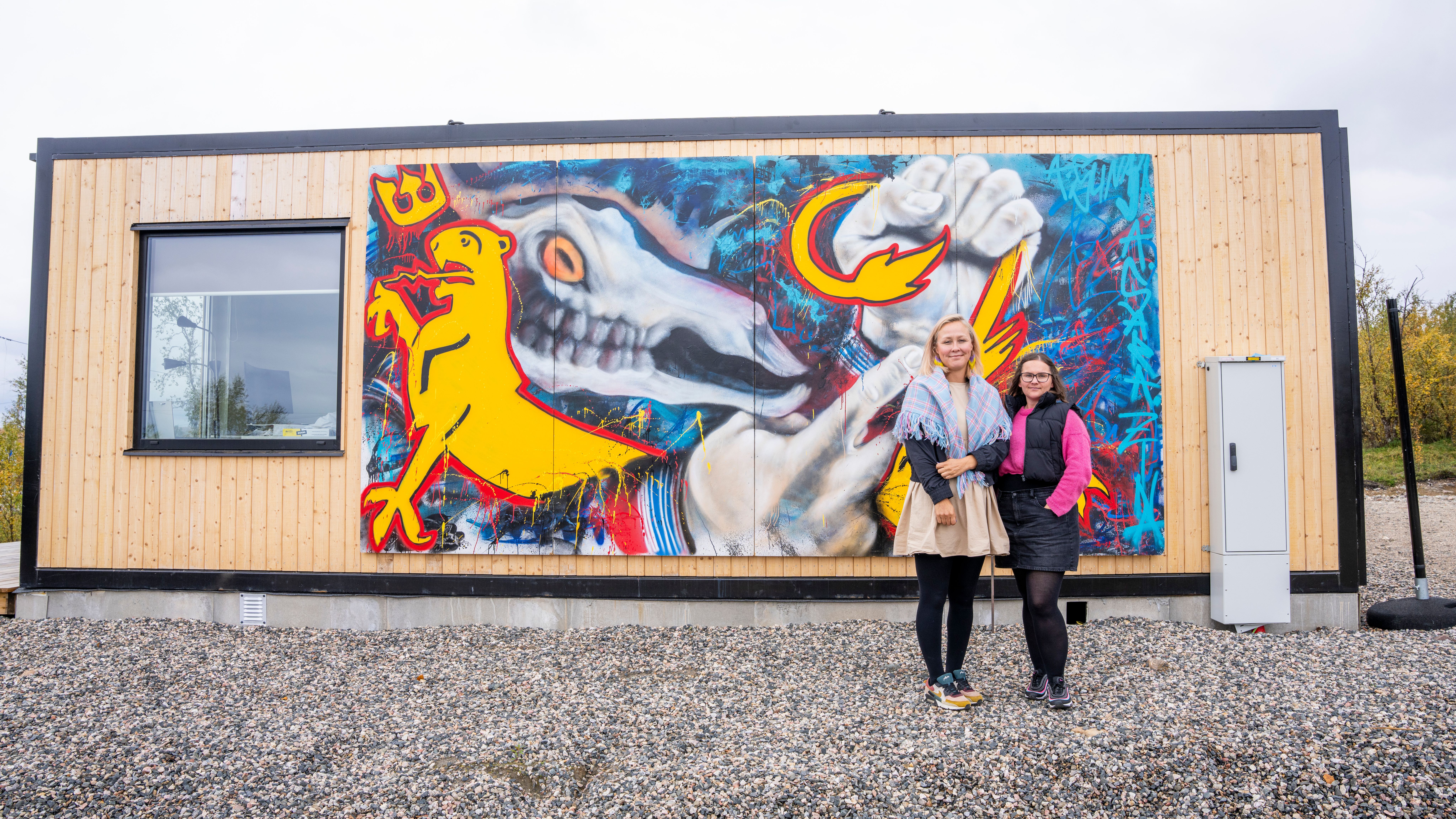 Dine Arnannguaq Fenger Lynge and Lina Márjá Karlsen in front of "Pile o Sápmi" artwork by Anders Sunna and Linda «Zina» Aslaksen