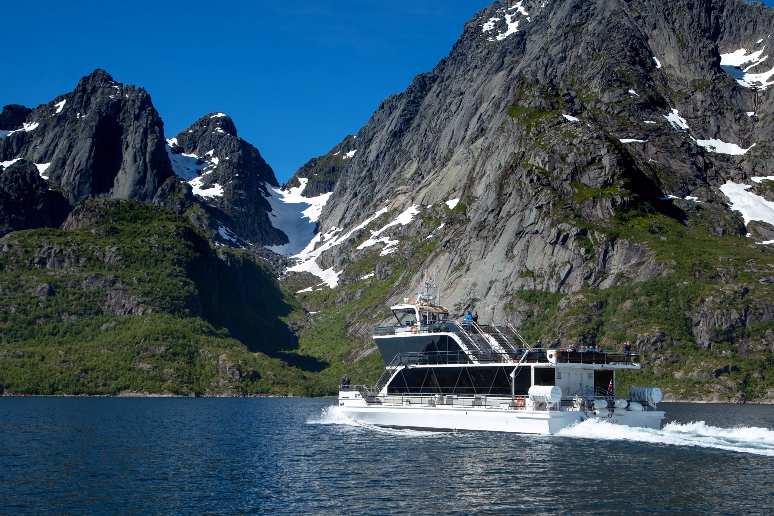 An electrical boat in the narrow Trollfjord in Lofoten under huge mountains.