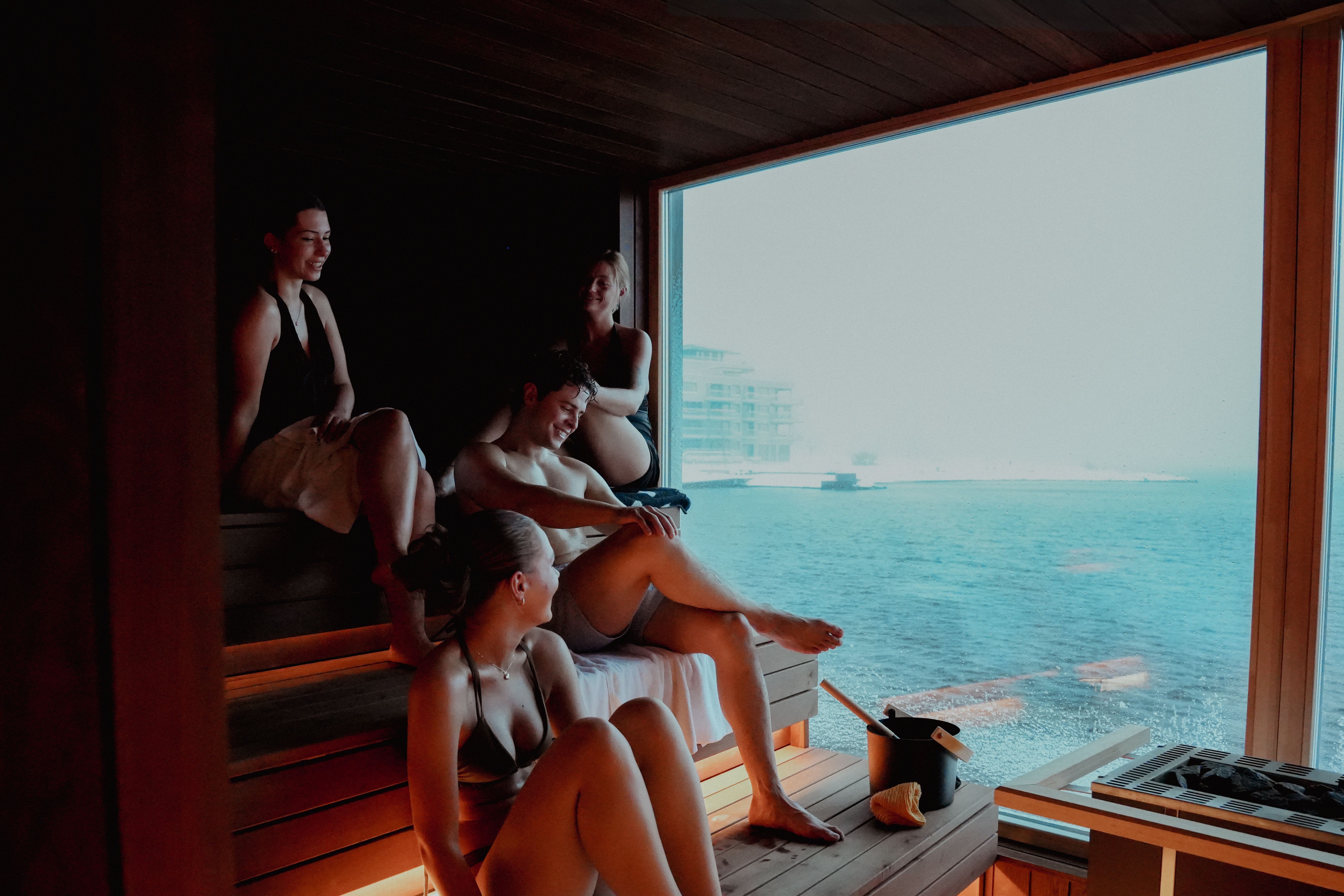 A group of friends sitting inside the sauna at Smeigedag Sauna, Bystranda in Kristiansand 