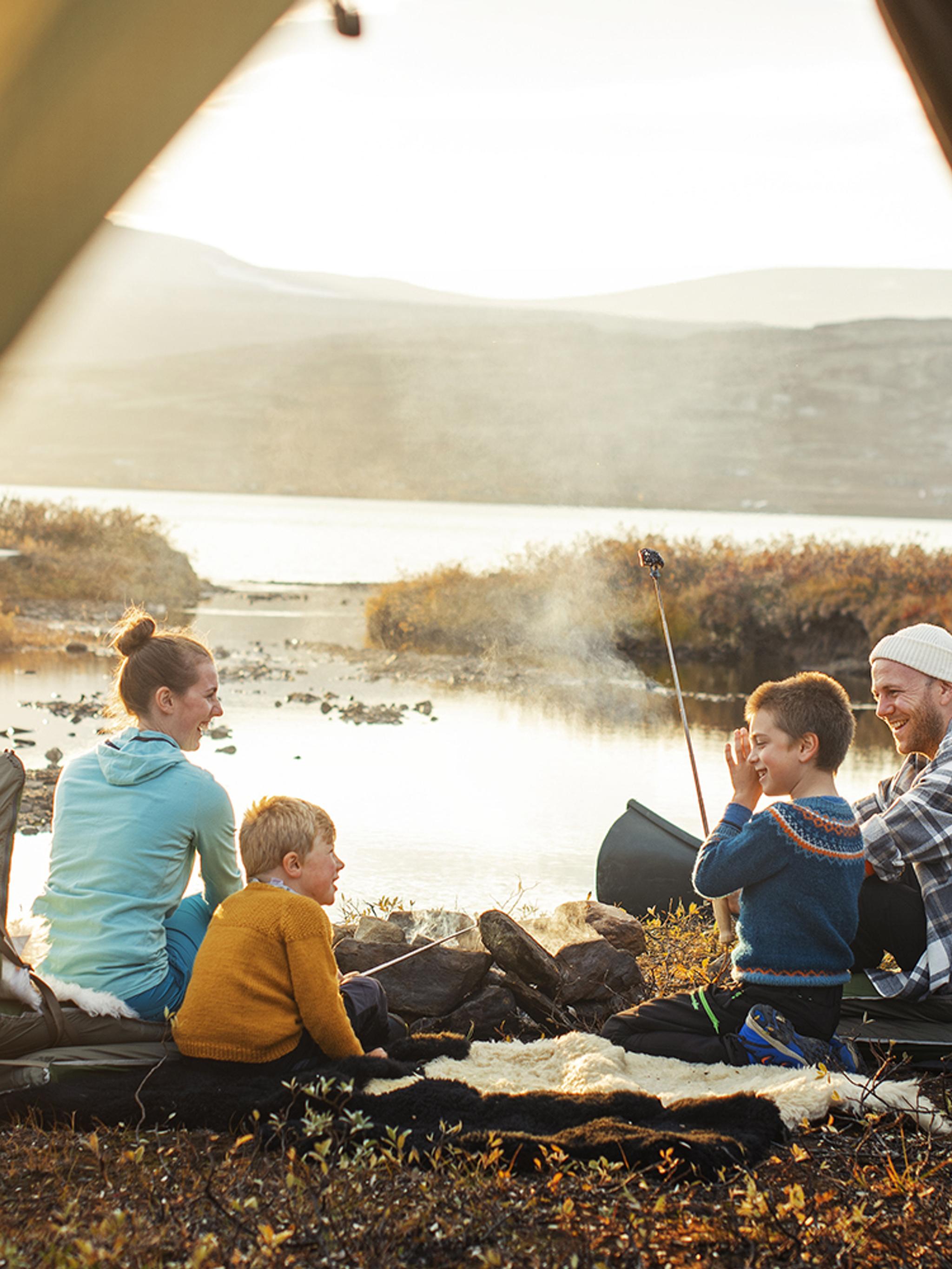 Familie på fire sitter ved et bål i Oppdal