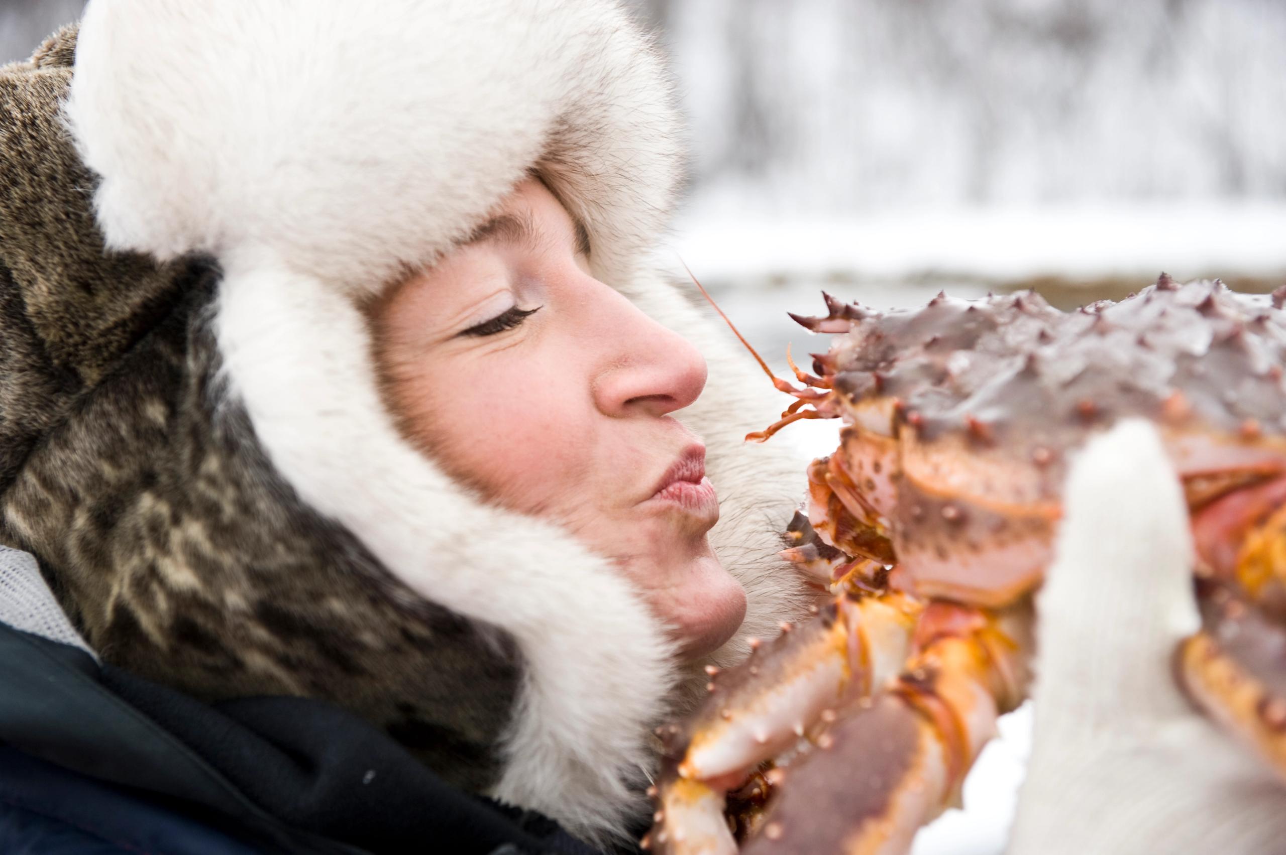 En kvinne kysser en kongekrabbe om vinteren, Norge