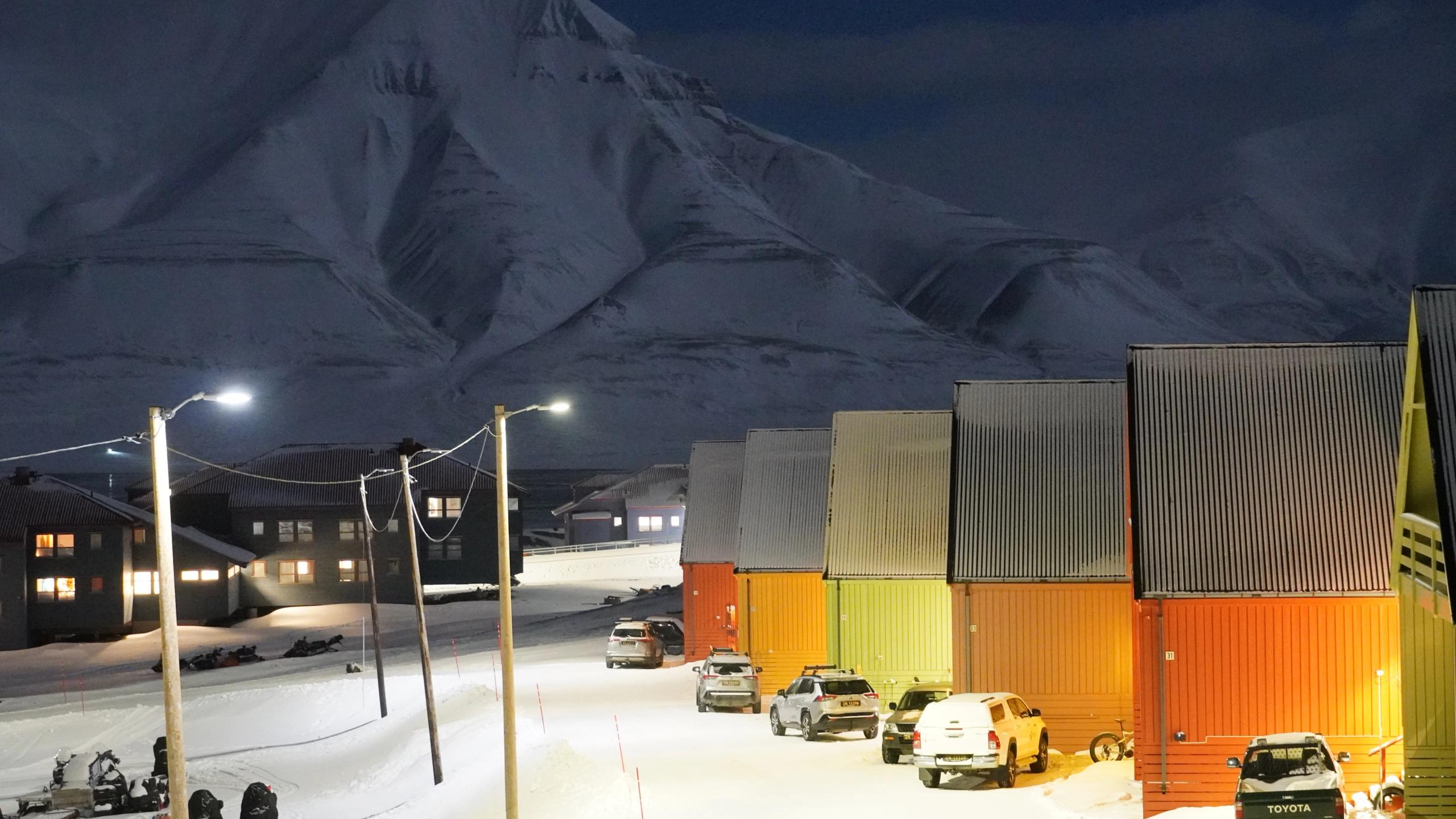 Colorful houses and snow mobiles in front of a white mountain