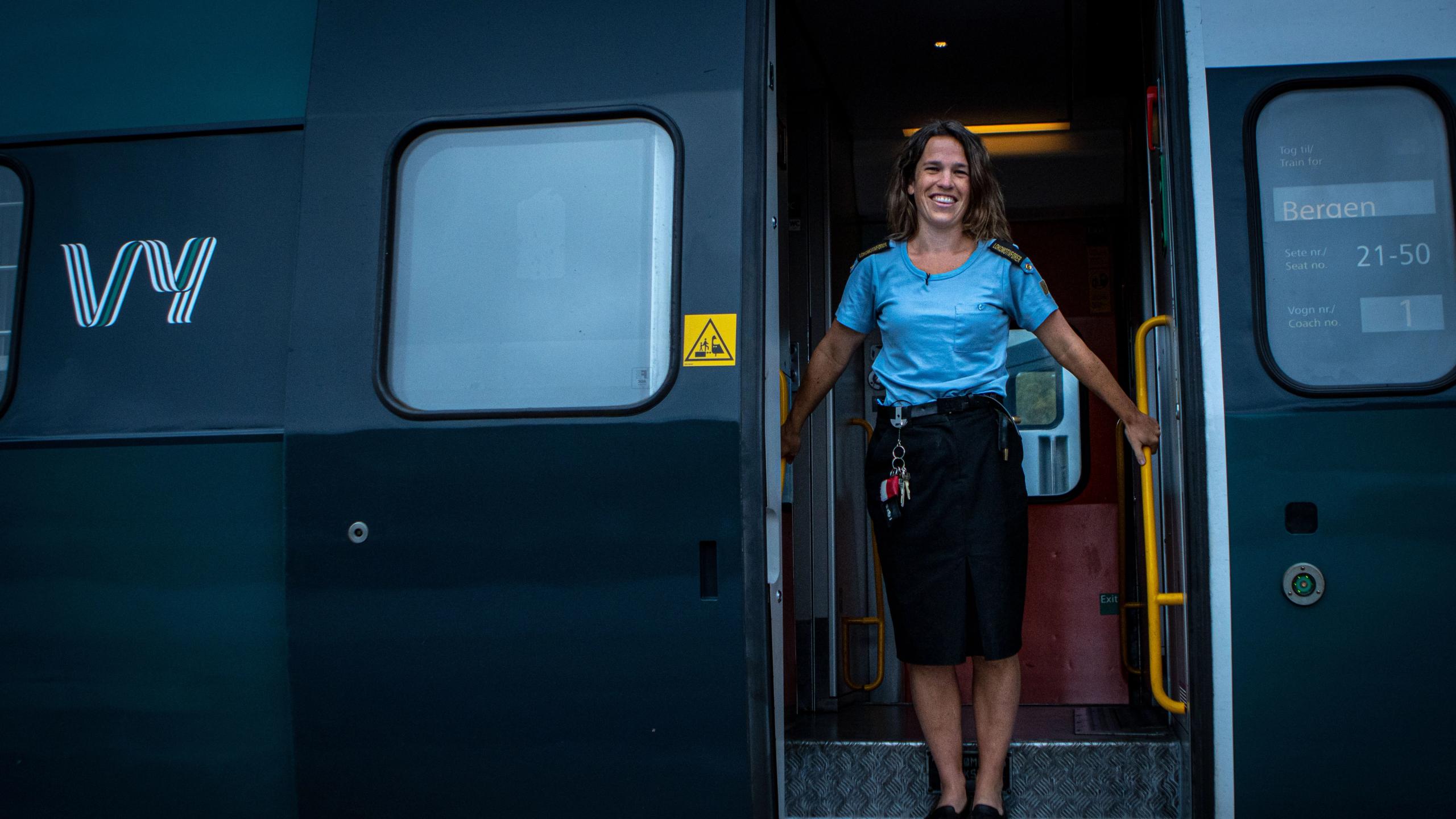 En lokfører står i inngangen til en av vognene