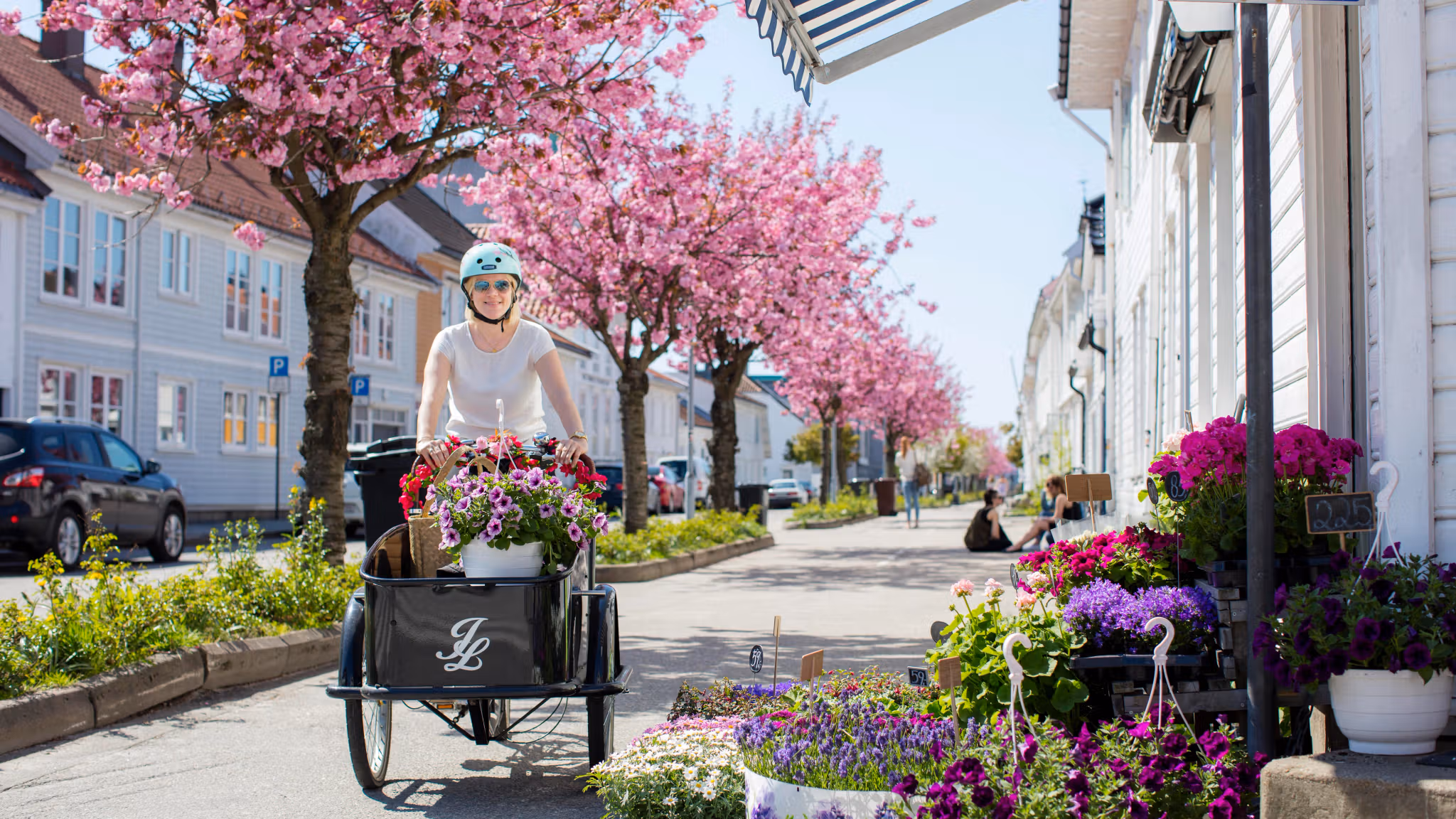 Una mujer pasea en una bicicleta cargada con plantas y flores por Posebyen, la ciudad vieja de Kristiansand, en el Sur de Noruega.