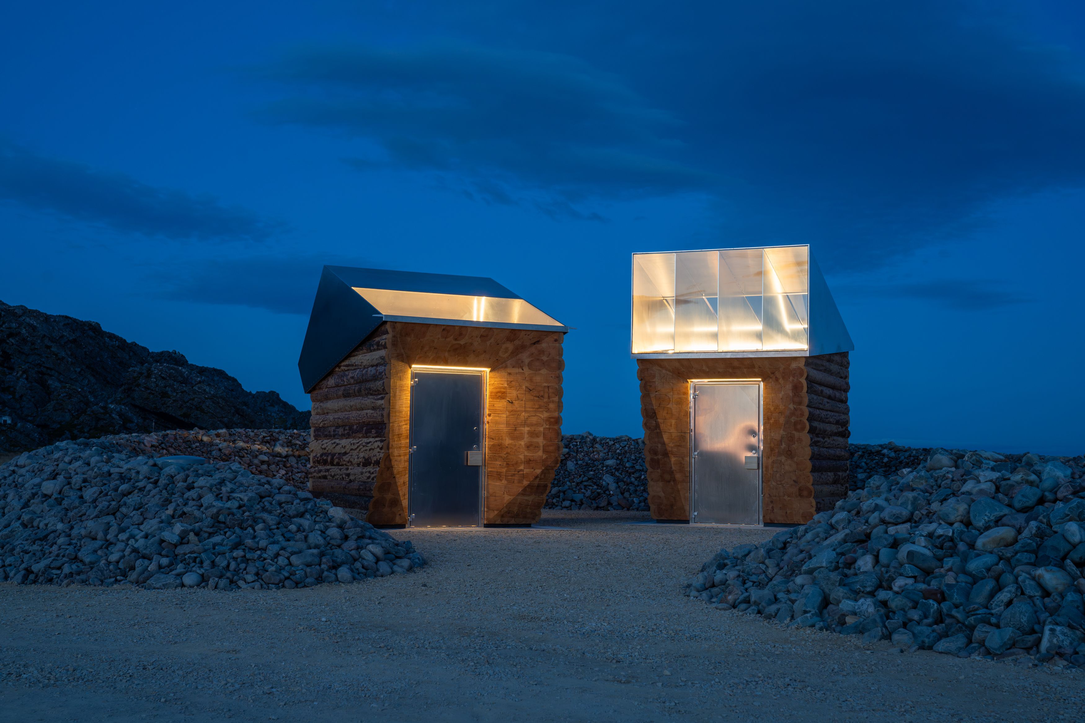 Two wooden buildings with glowing light against the night sky