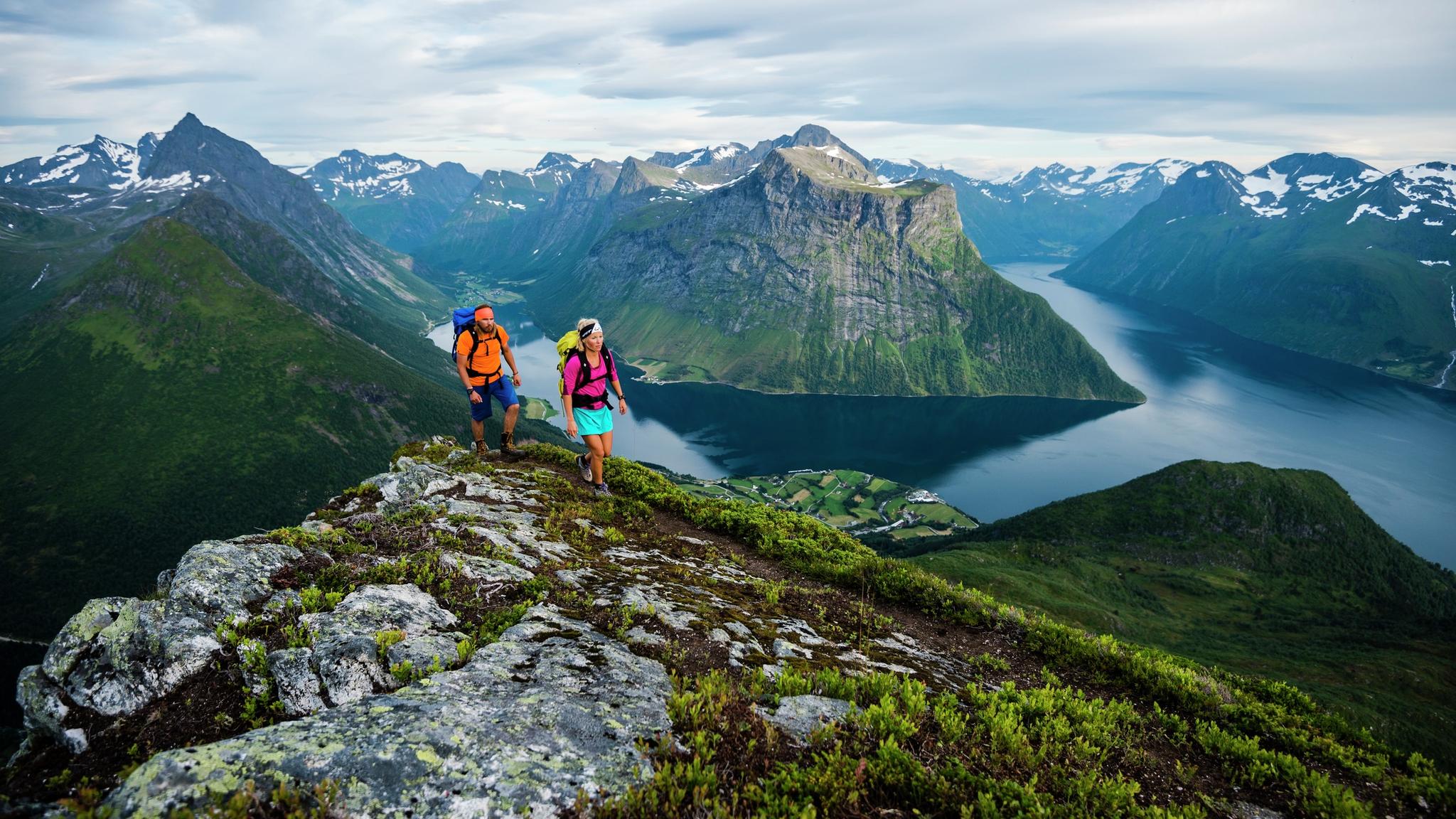 Two people are hiking the mountains of Hjørundfjorden in Fjord Norway