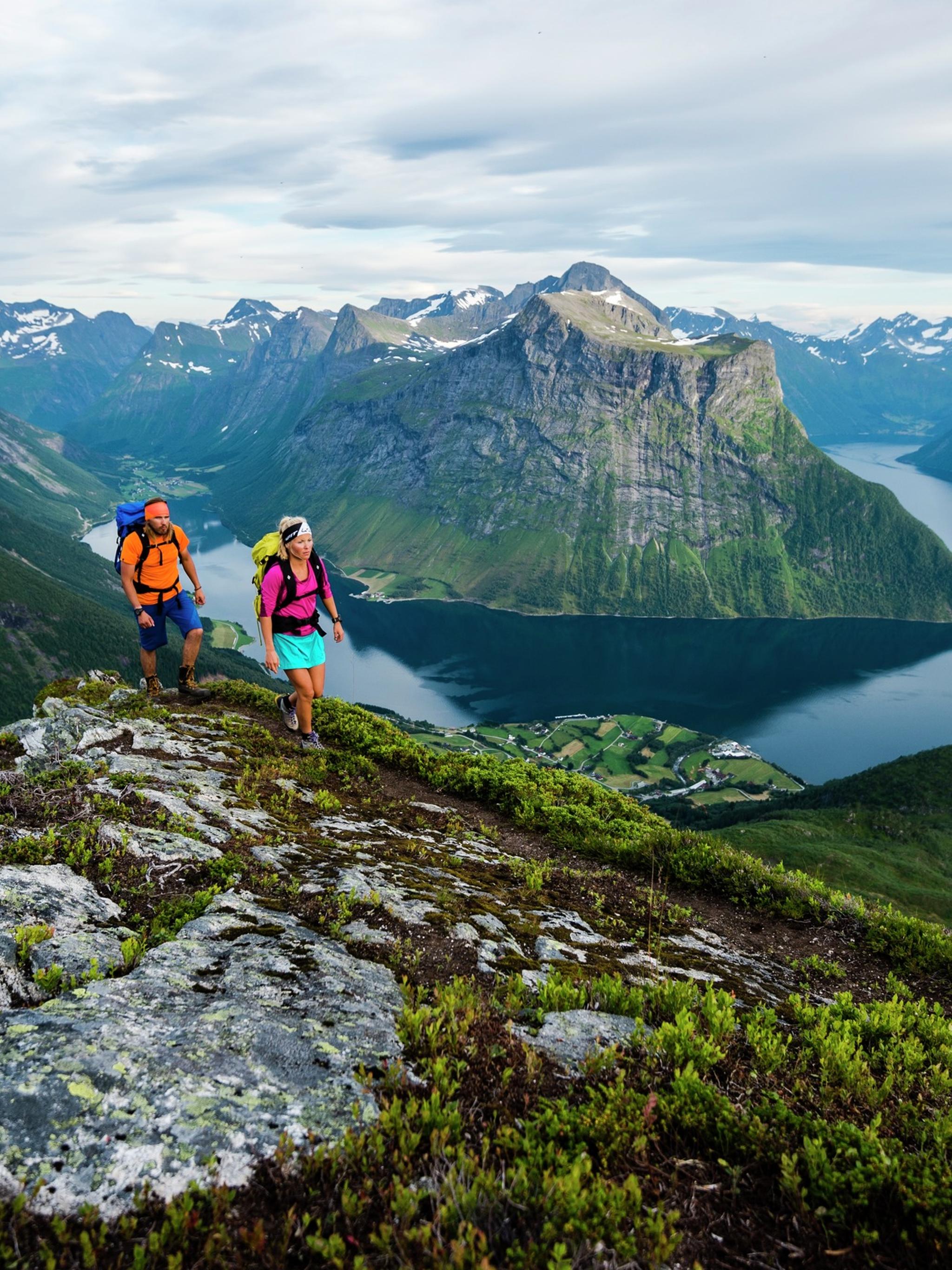 Two people are hiking the mountains of Hjørundfjorden in Fjord Norway