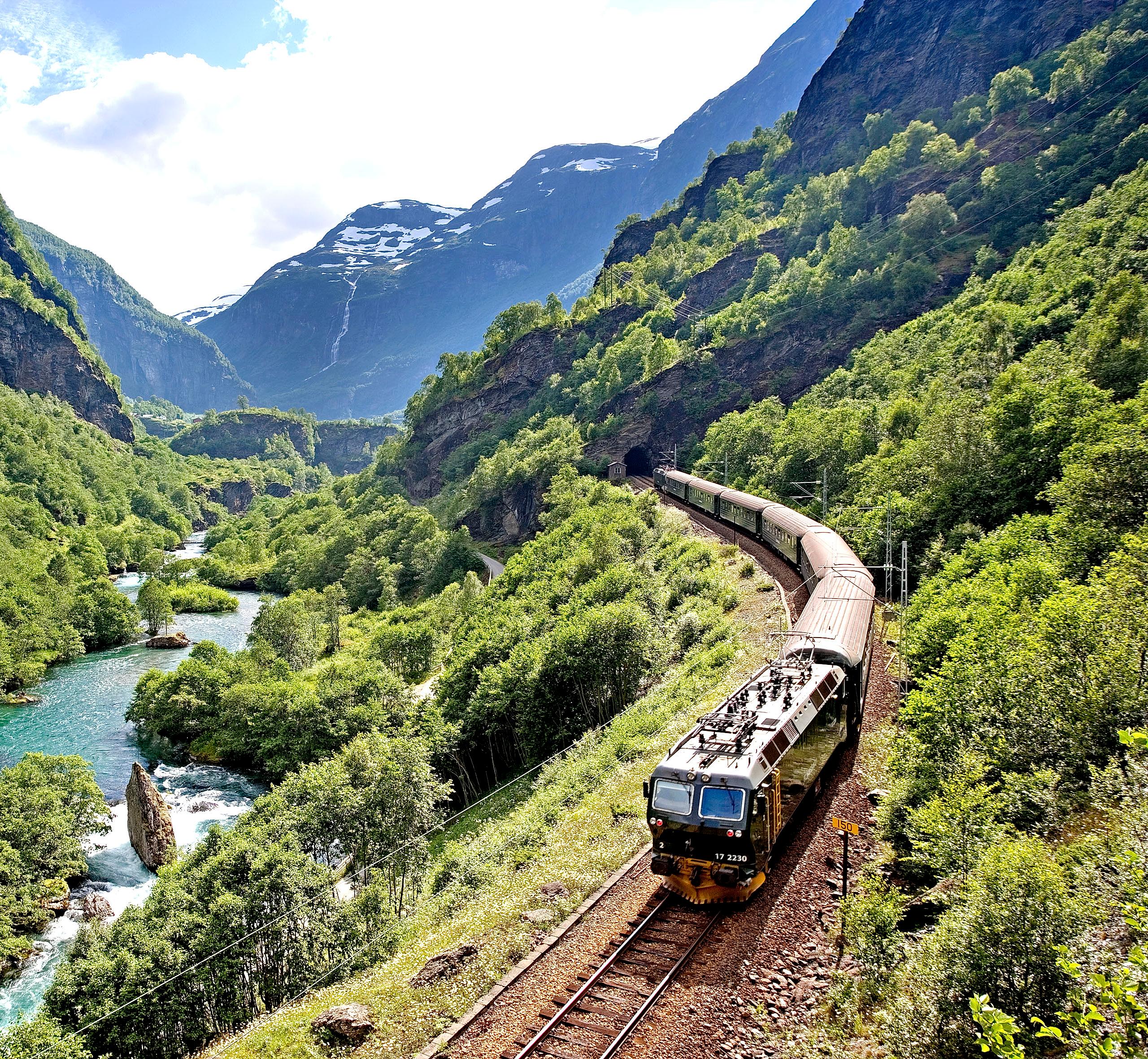 The Flåm railway going through the landscape of green hills and spectacular mountains in Fjord Norway