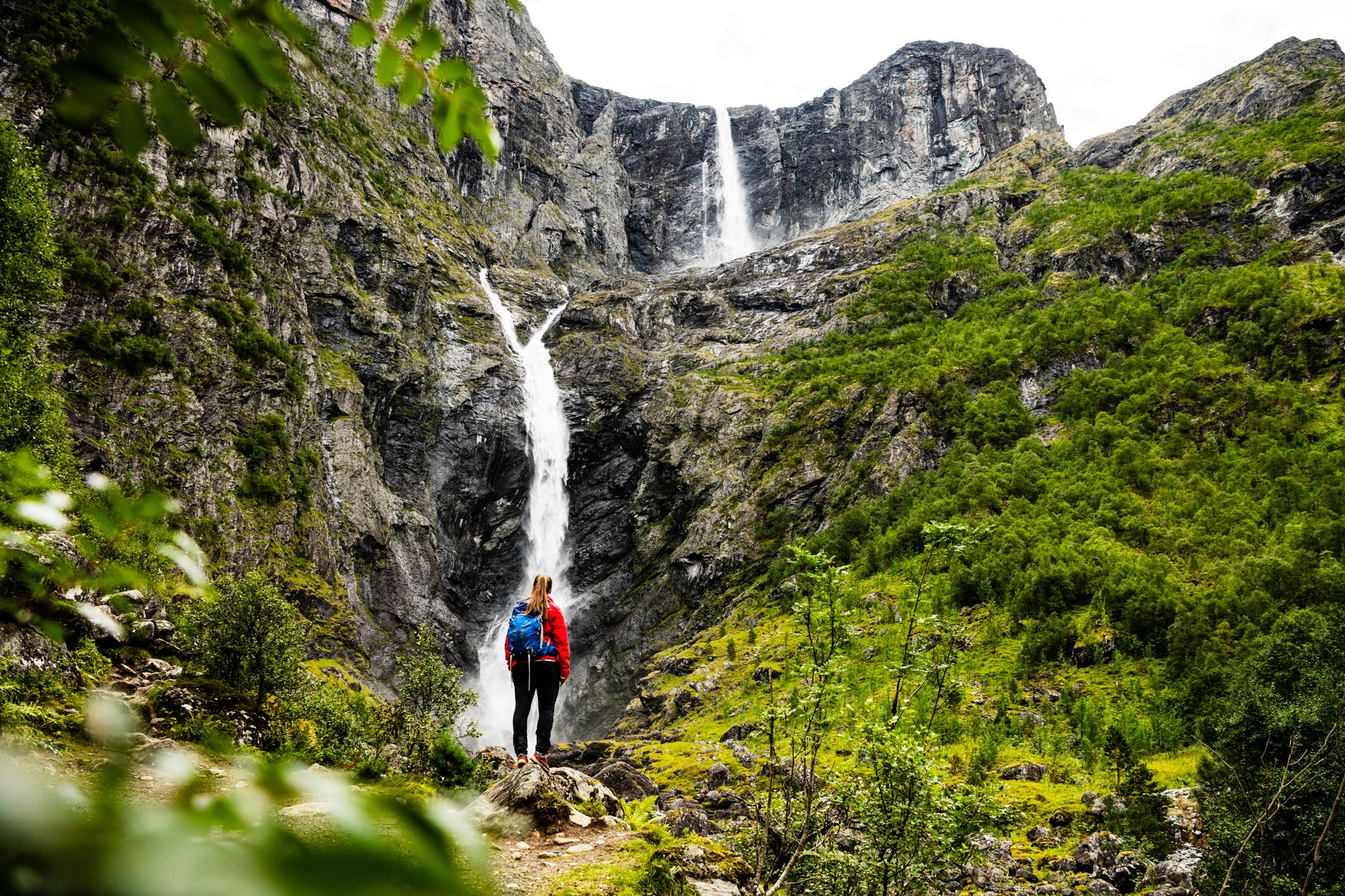 A woman is standing in front of the Mardalsfossen waterfall in Molde during summer. Northwest, Fjord Norway.