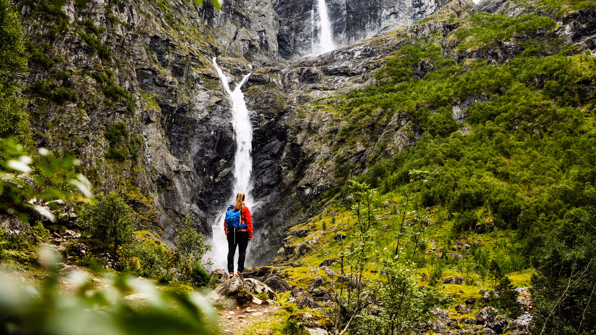 A woman is standing in front of the Mardalsfossen waterfall in Molde during summer. Northwest, Fjord Norway.