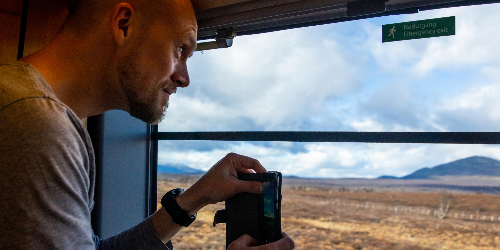 En mann tar bilde på Dovrefjell på Dovrebanen