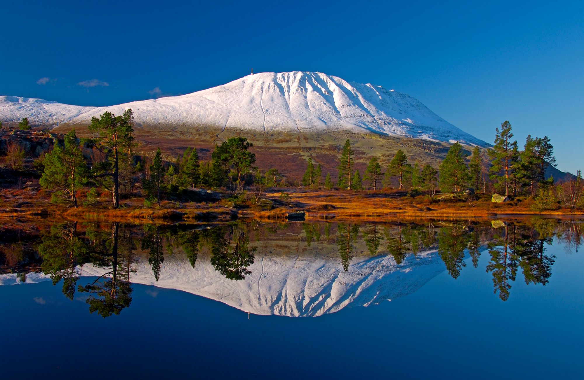 A snow-covered Gaustatoppen reflecting in a lake, Telemark, Norway