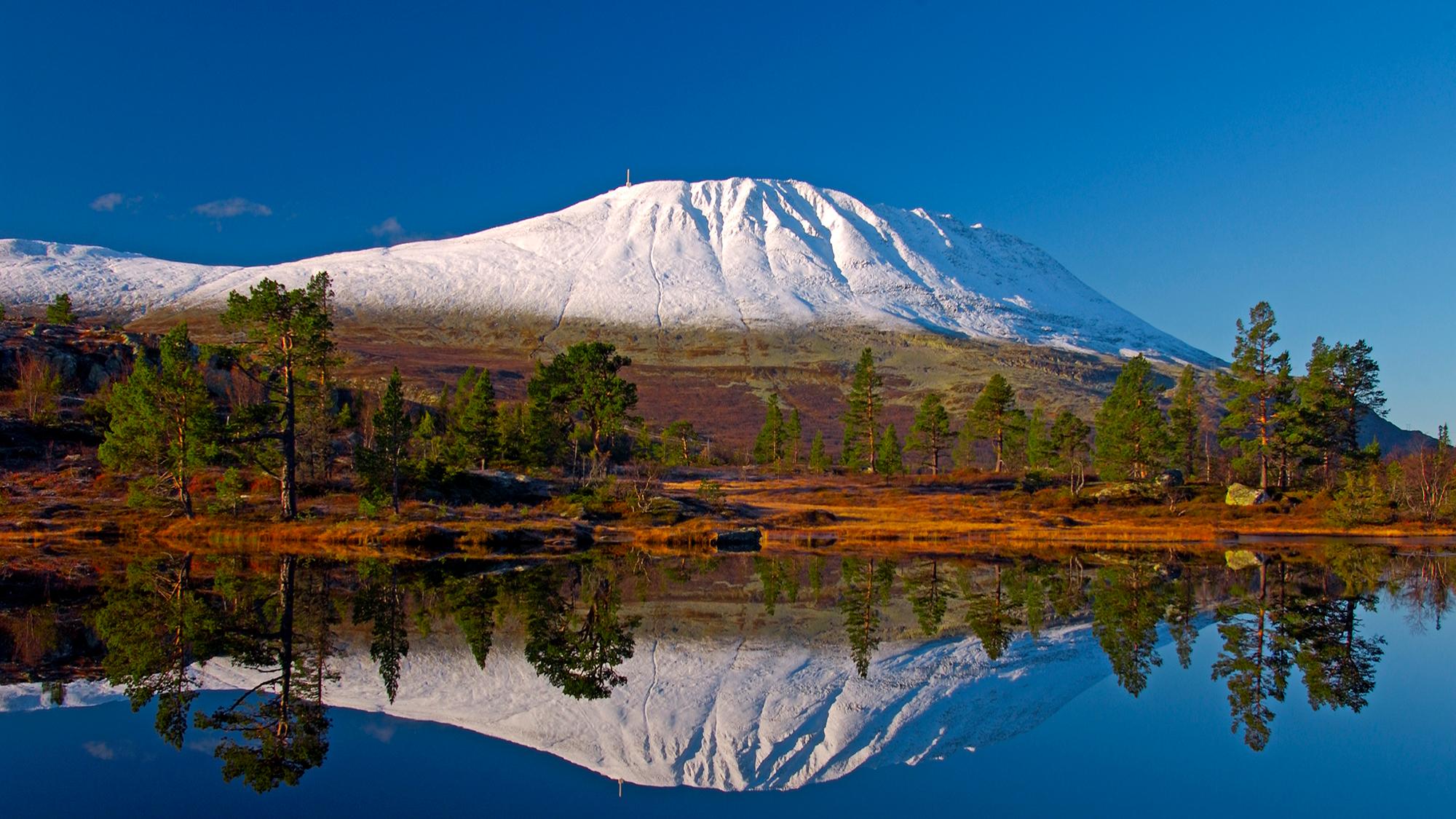 En snødekket Gaustatoppen speiler seg i en innsjø utenfor Rjukan i Telemark på Østlandet