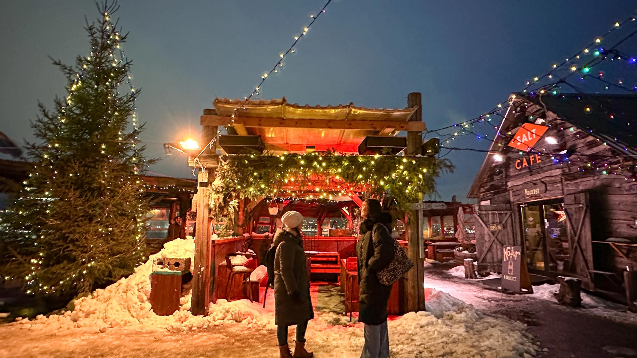 Two people in front of a Christmas stall at night at SALT in Oslo