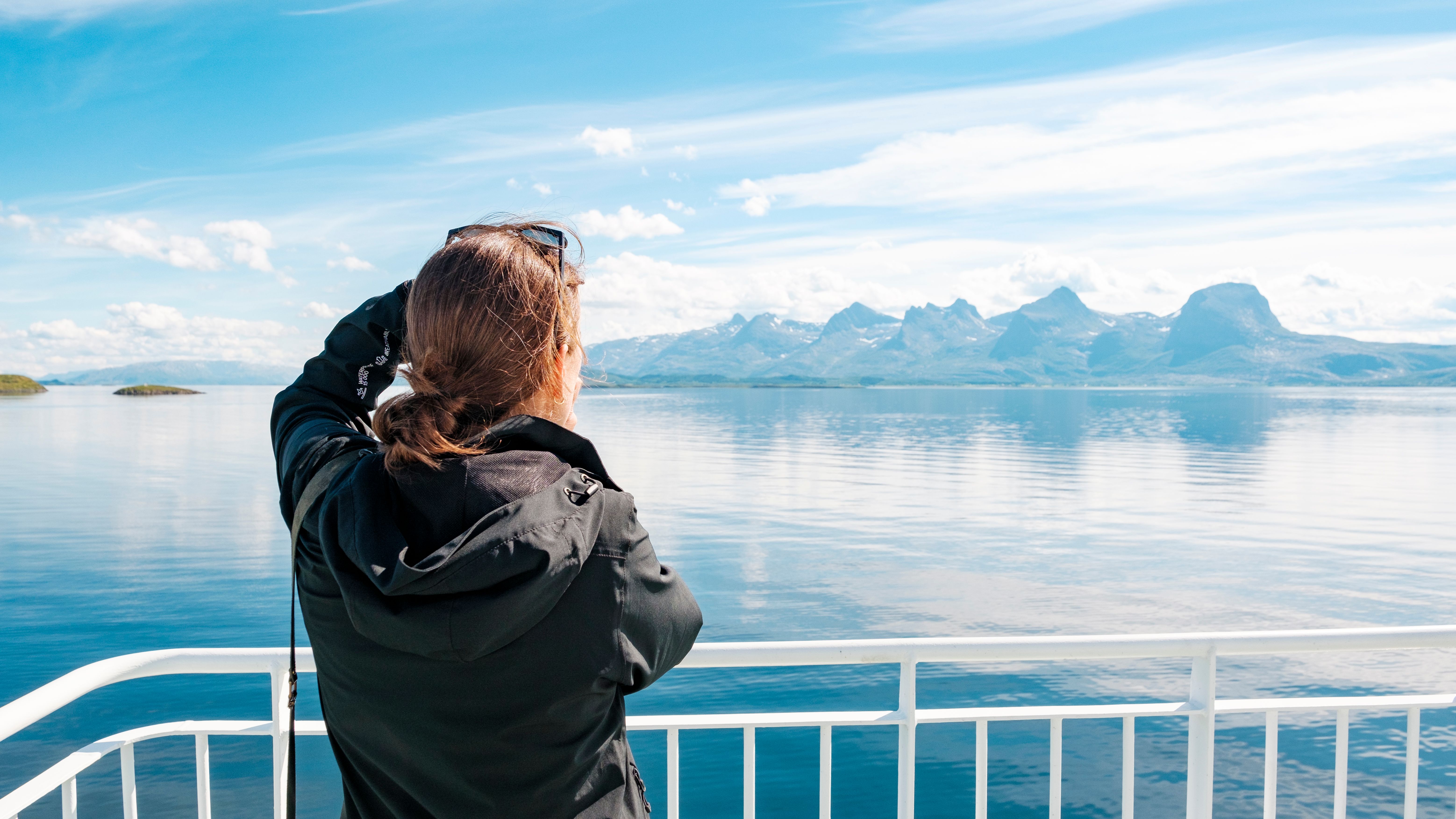 A woman taking a picture of the Seven Sisters mountains.