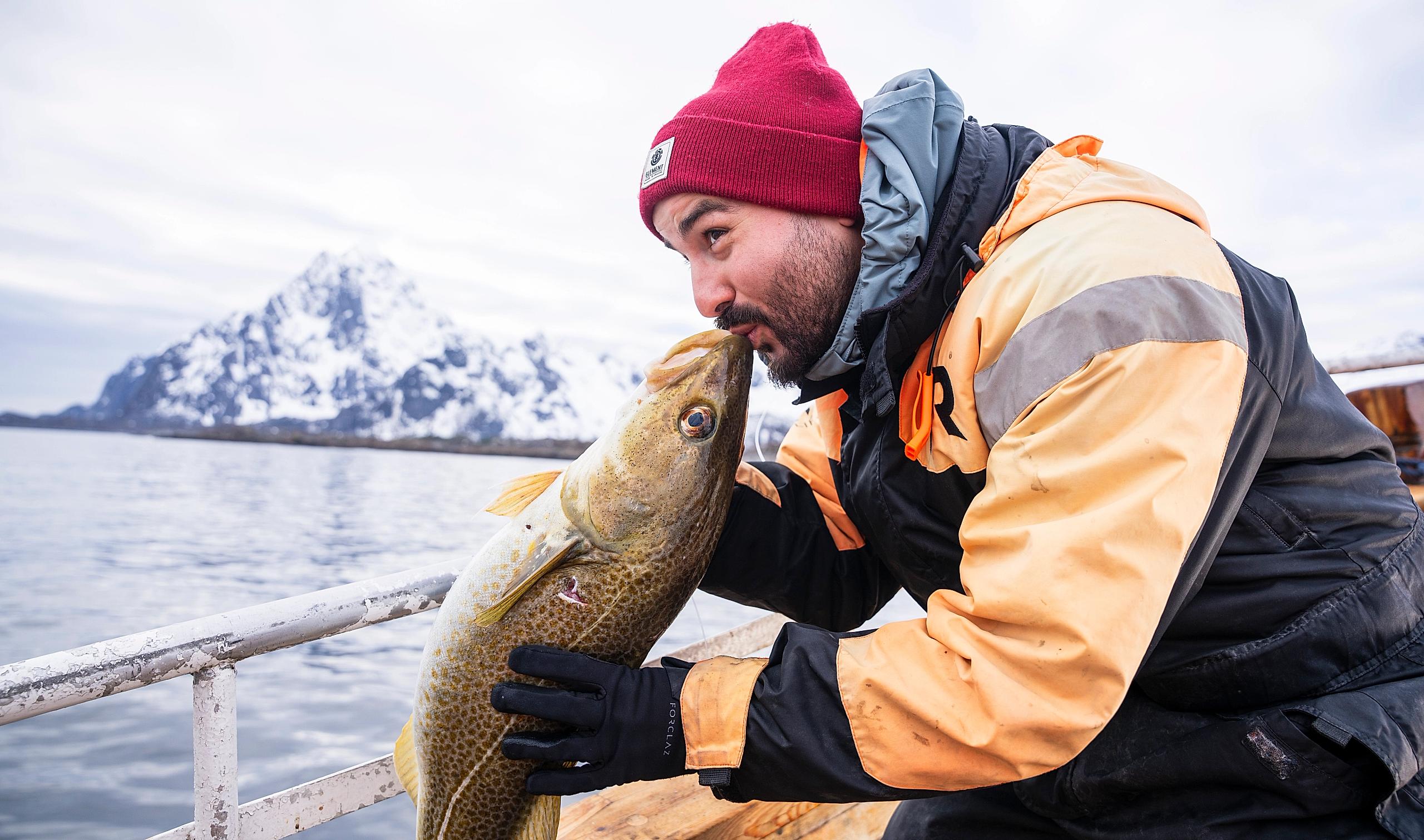 Man kissing an Arctic cod on a fishing trip