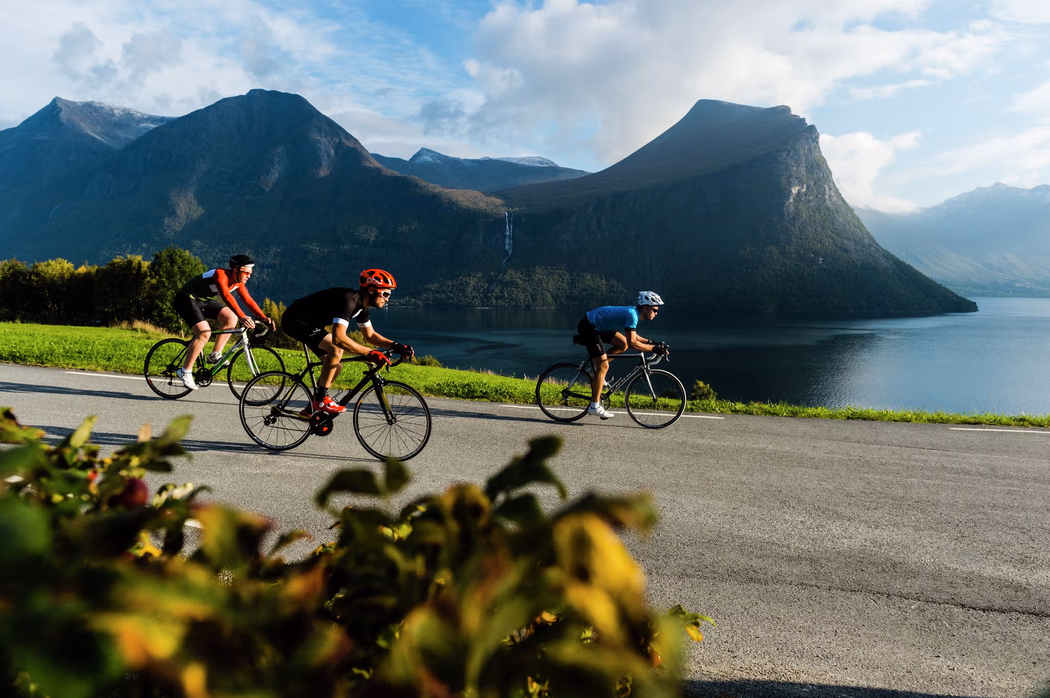 Three people road cycling along Isfjorden in Fjord Norway