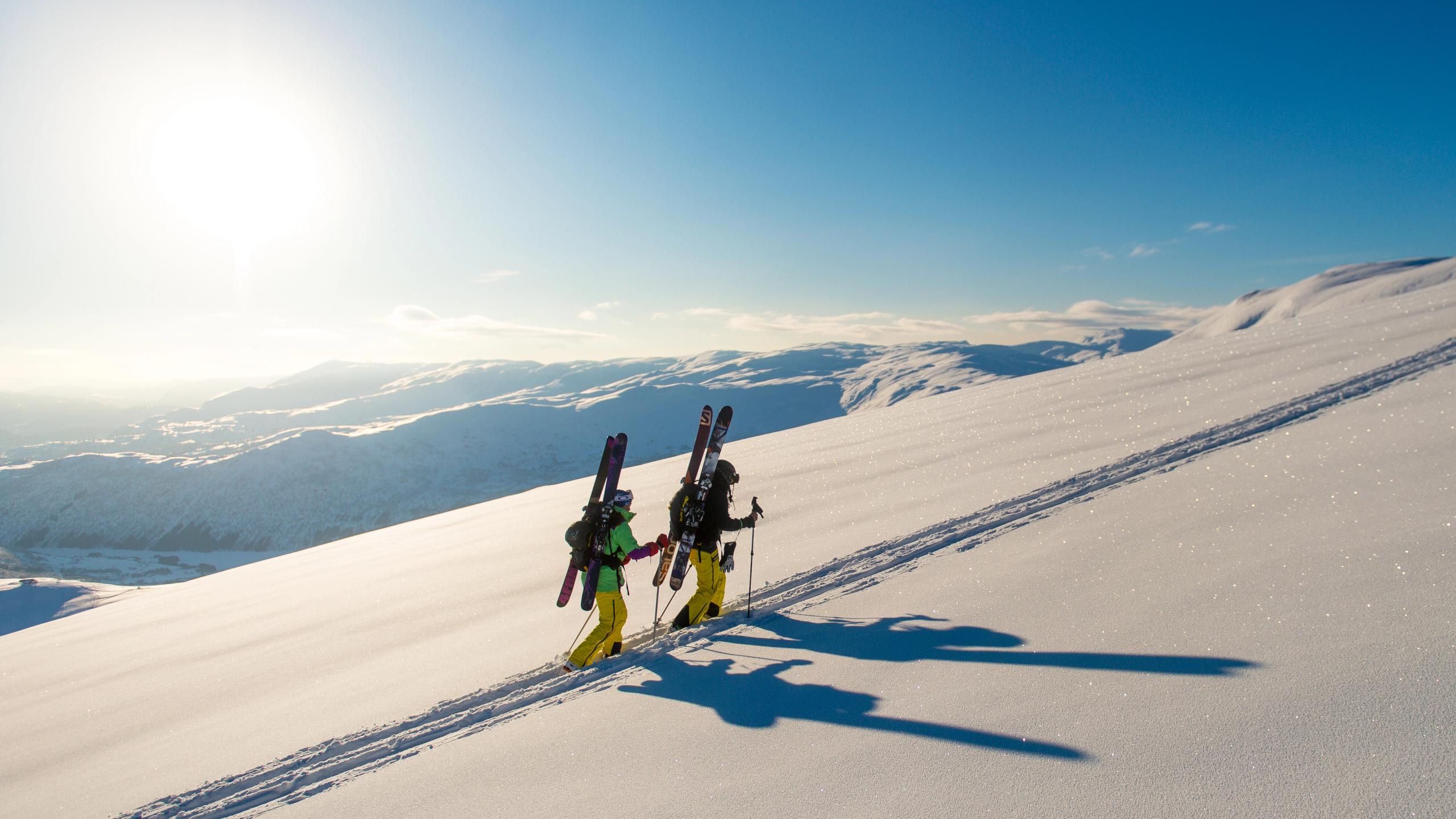 Two people are walking with their skis on their back towards a top in Myrkdalen, Fjord Norway