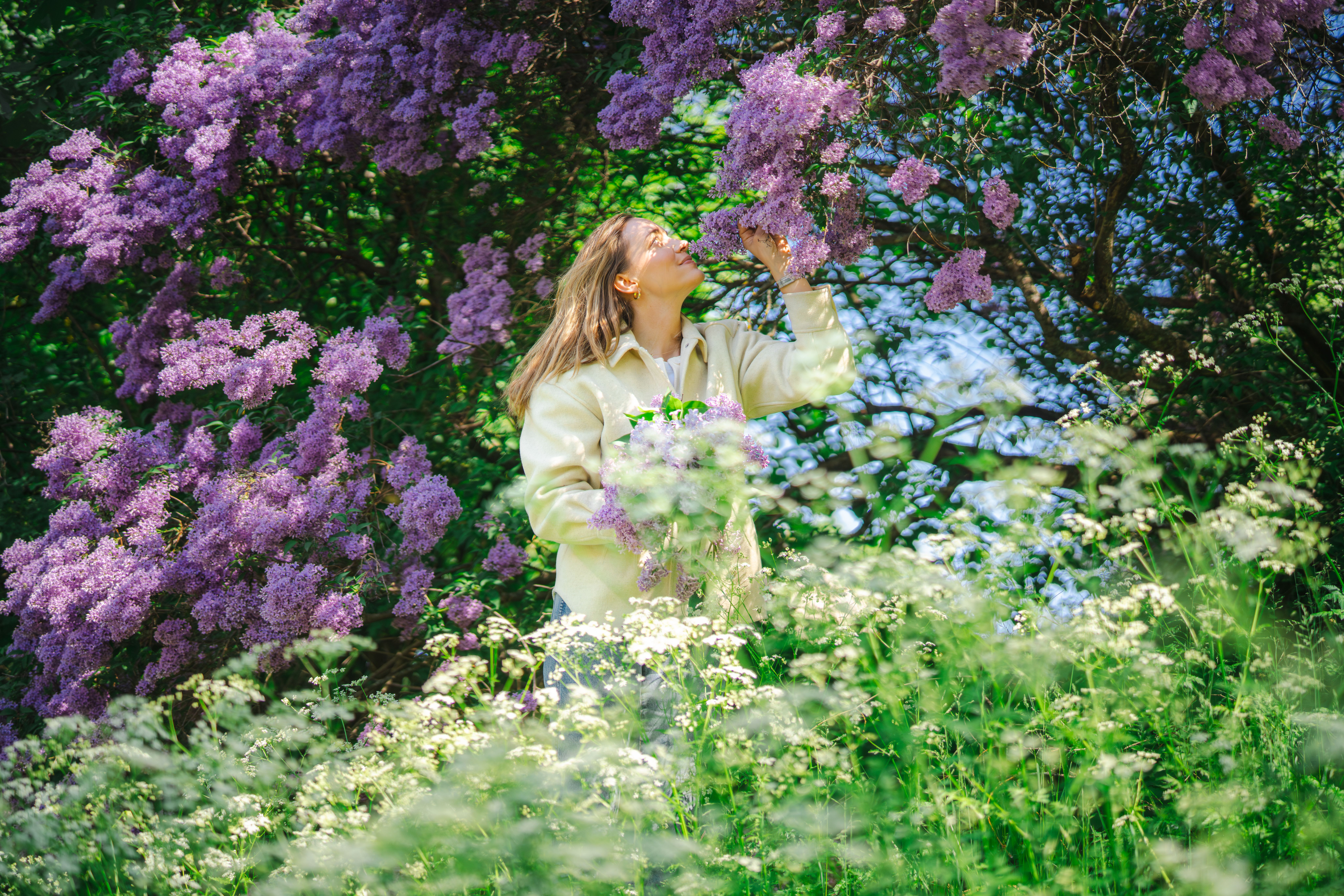 A woman smelling purple flowers.