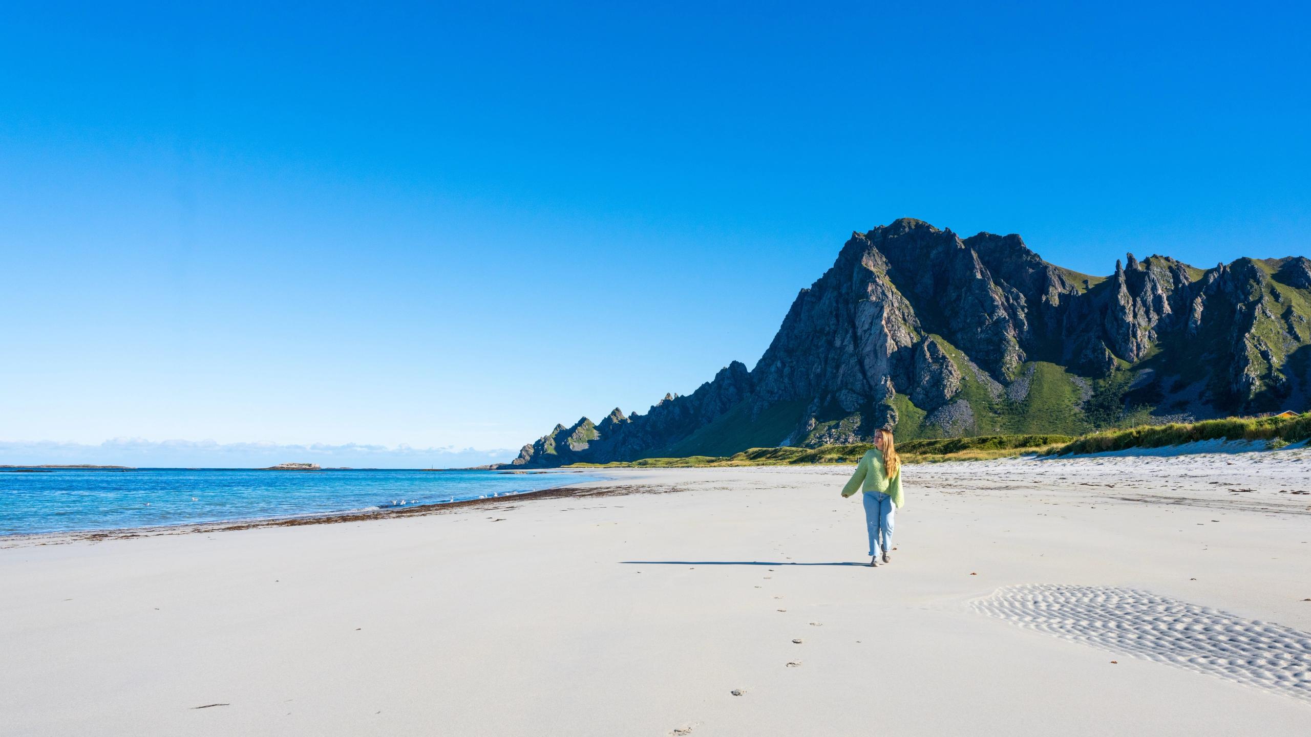 En dame går på Bleikstranda på Andøya