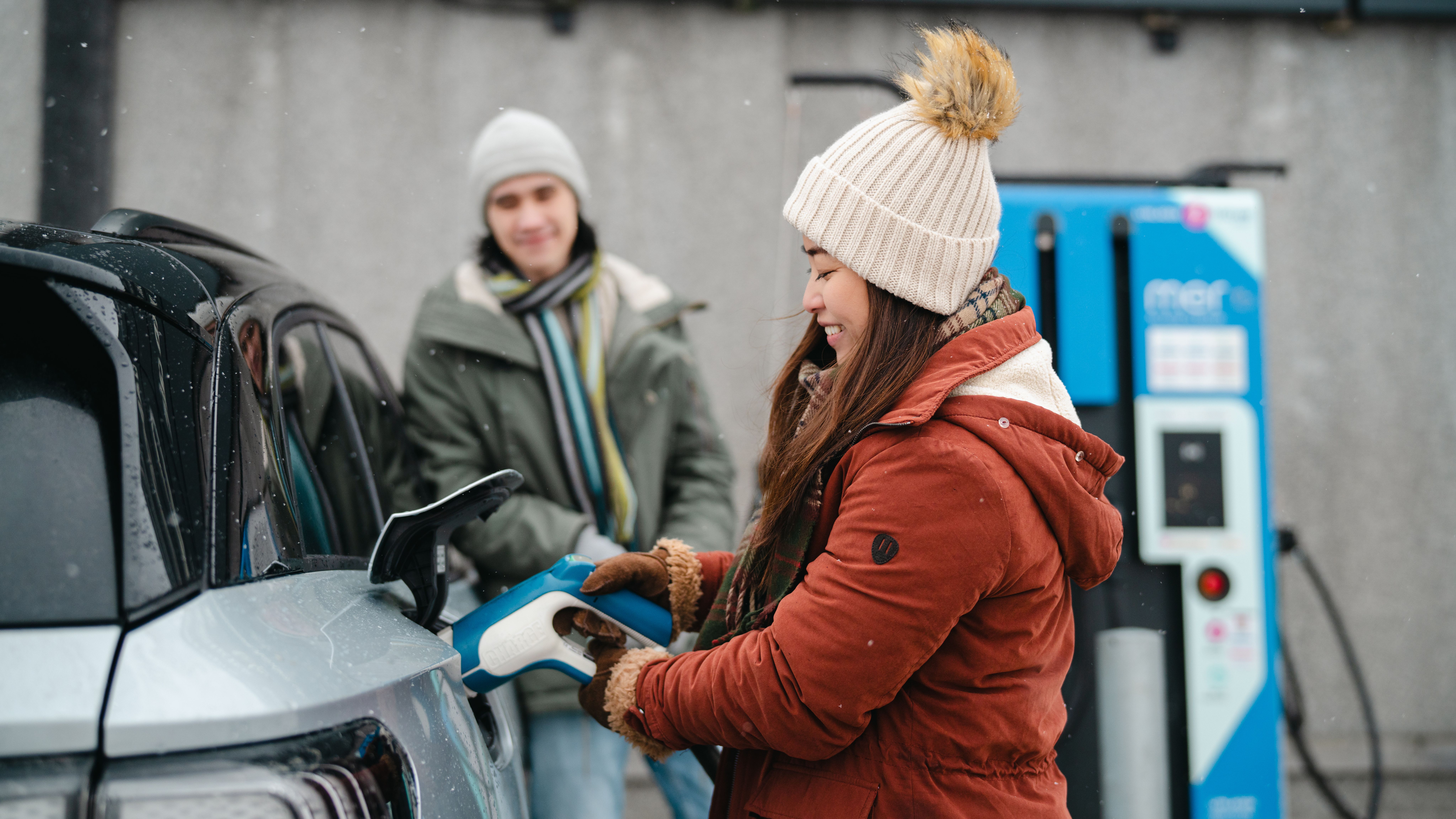A woman charging a electric car in winter, Tromsø