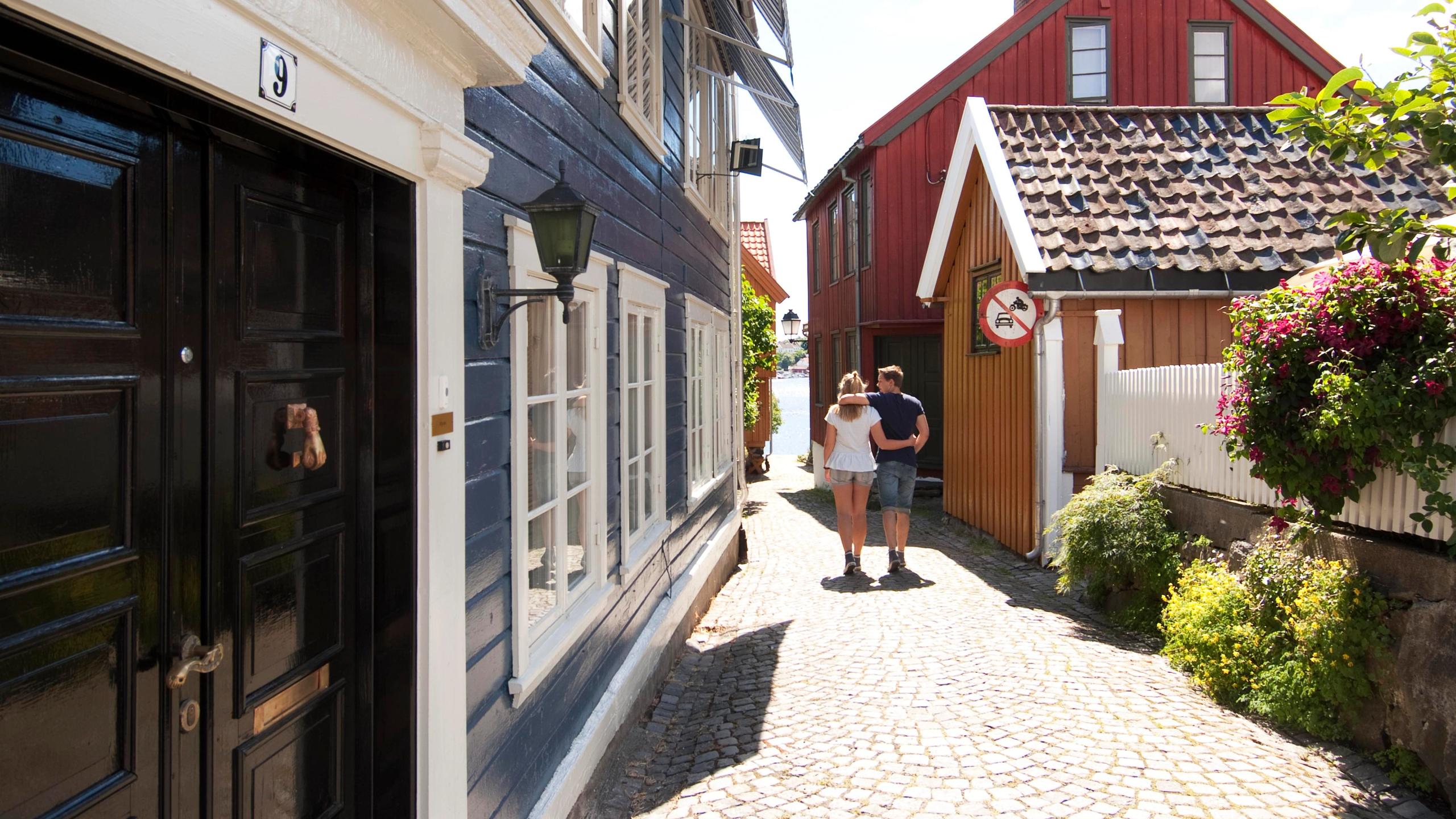 Et par går nedover en brusteinsgate i Gamlebyen i Arendal på Sørlandet.