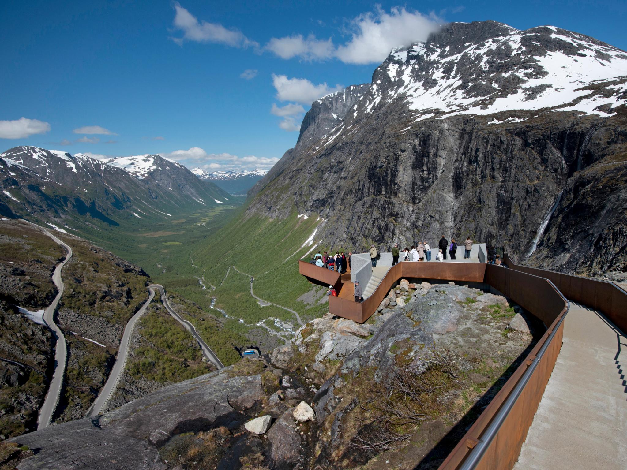 Folk beundrer utsikten over Nasjonal turistveg Trollstigen på Vestlandet fra et stilig utsiktspunkt