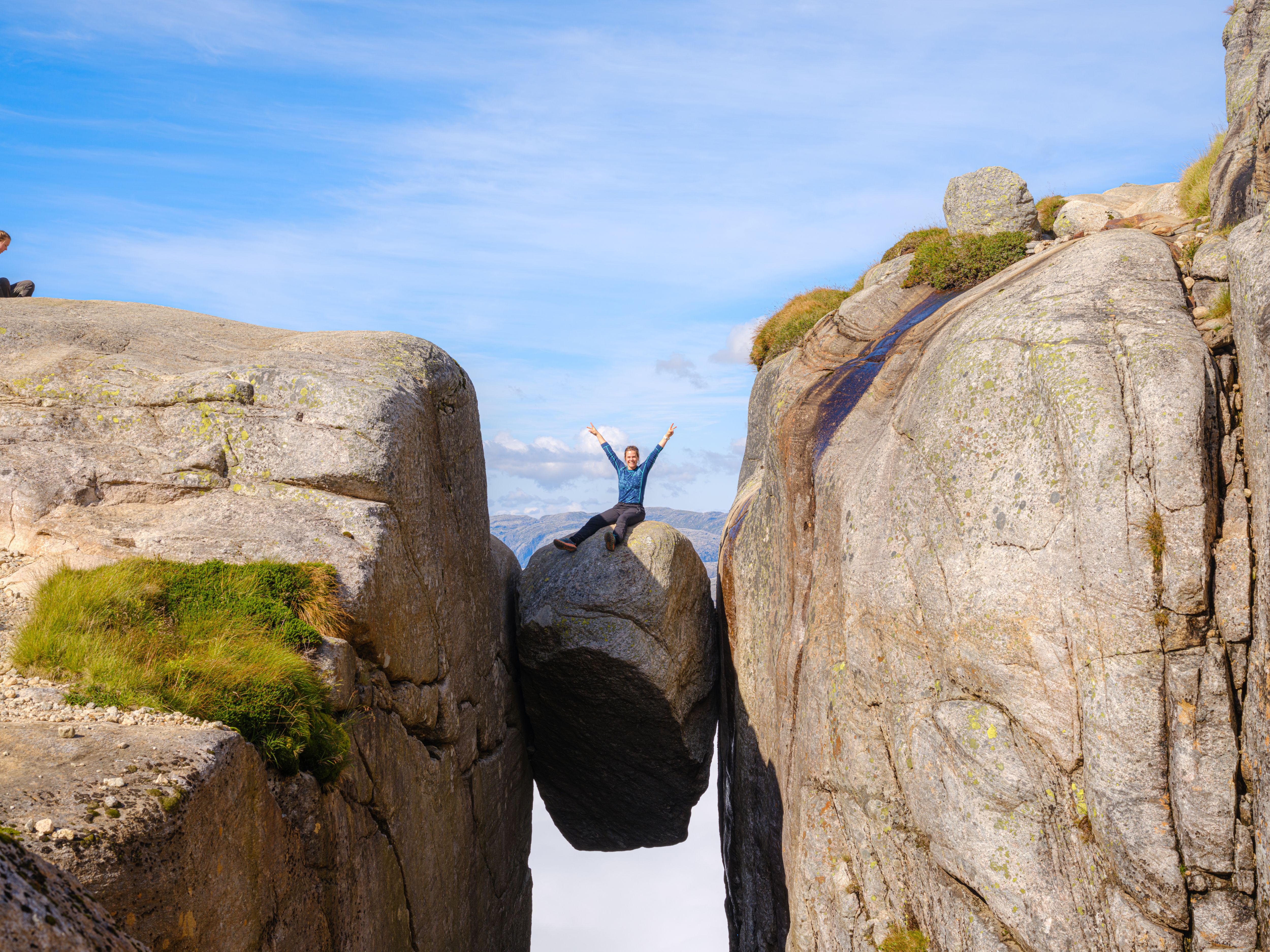 Woman sitting on Kjeragbolten in Lysefjord, Fjord Norway