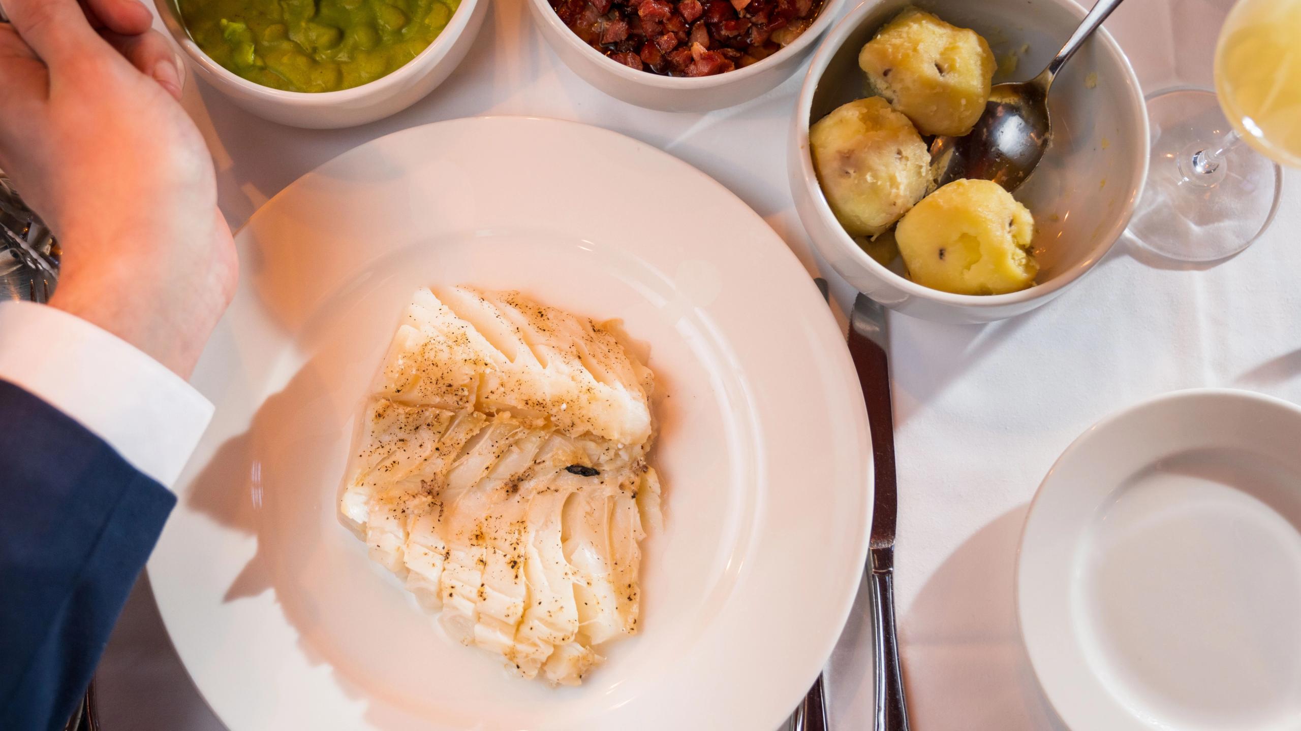 En porsjon med lutefisk, servert med potet, bacon og ertestuing