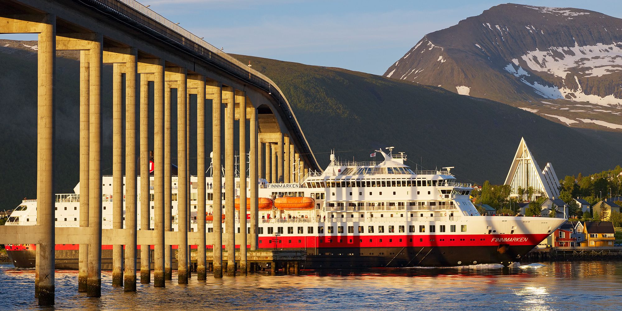 Un barco Hurtigruten avanza por debajo de un puente en Tromsø, Norte de Noruega.