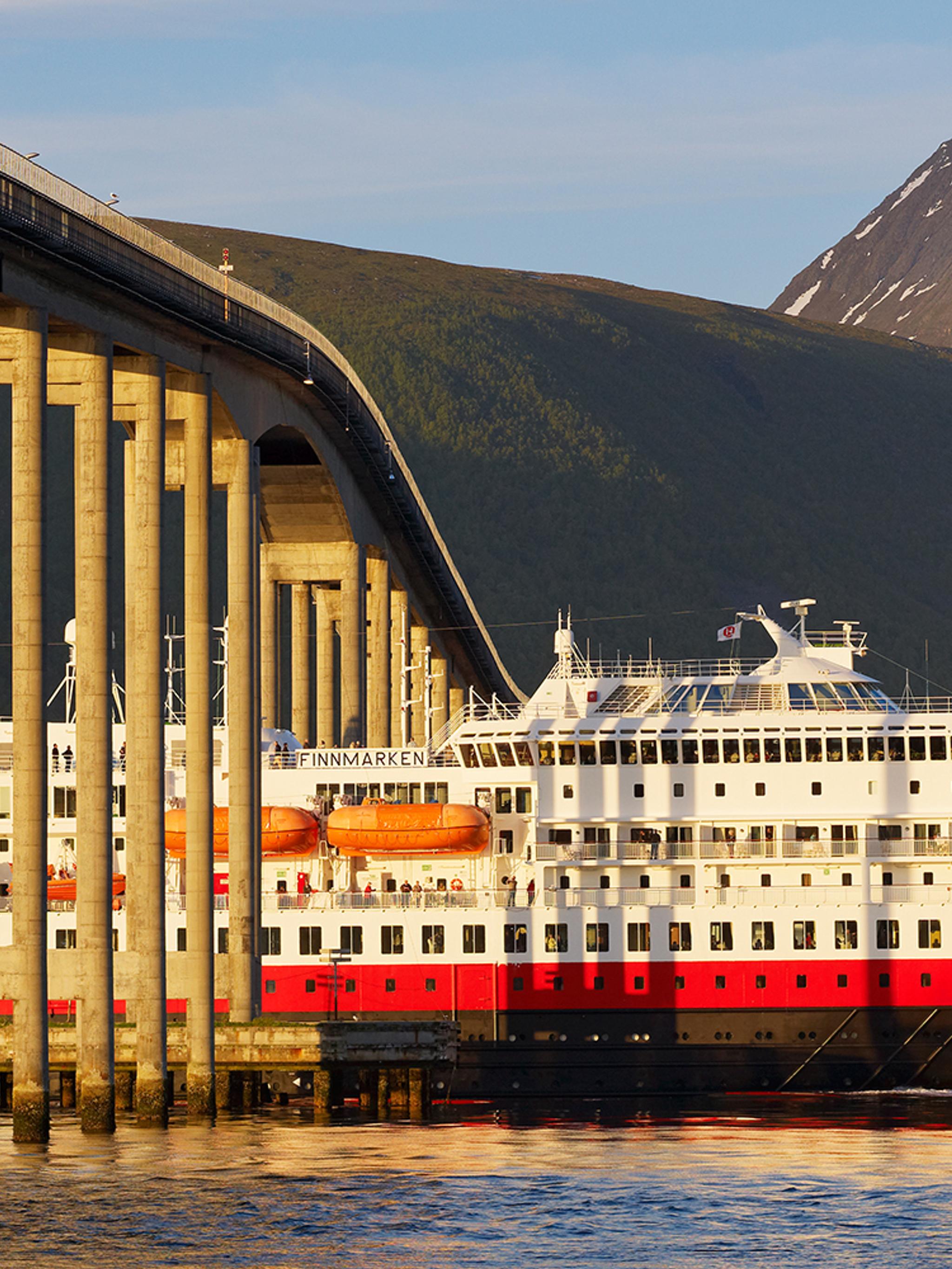 Un barco Hurtigruten avanza por debajo de un puente en Tromsø, Norte de Noruega.
