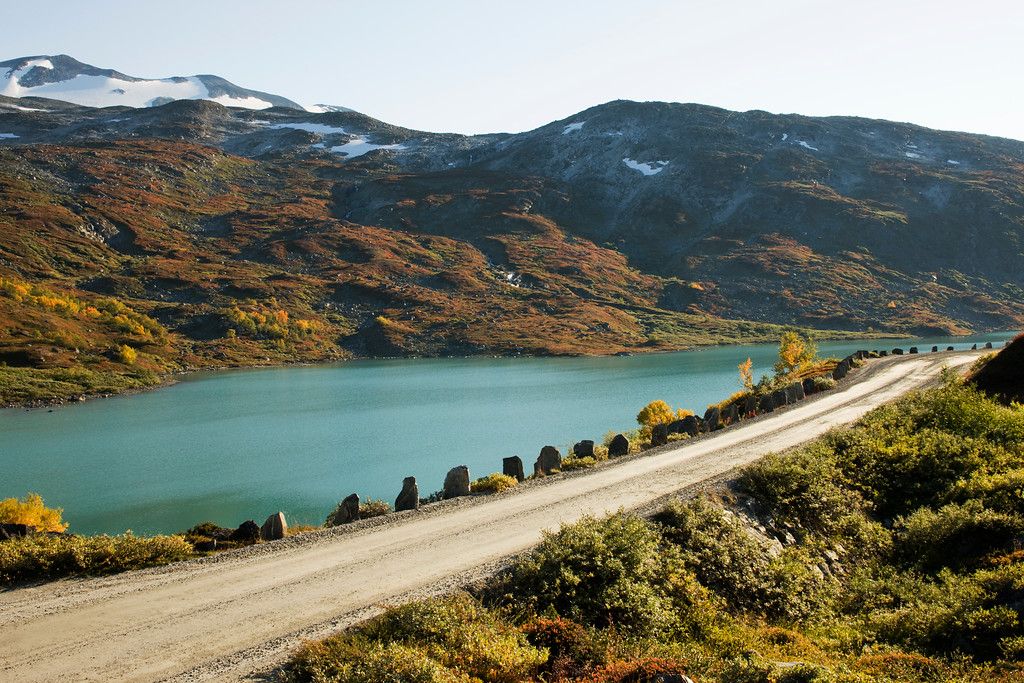 A road right next to a bright blue lake.