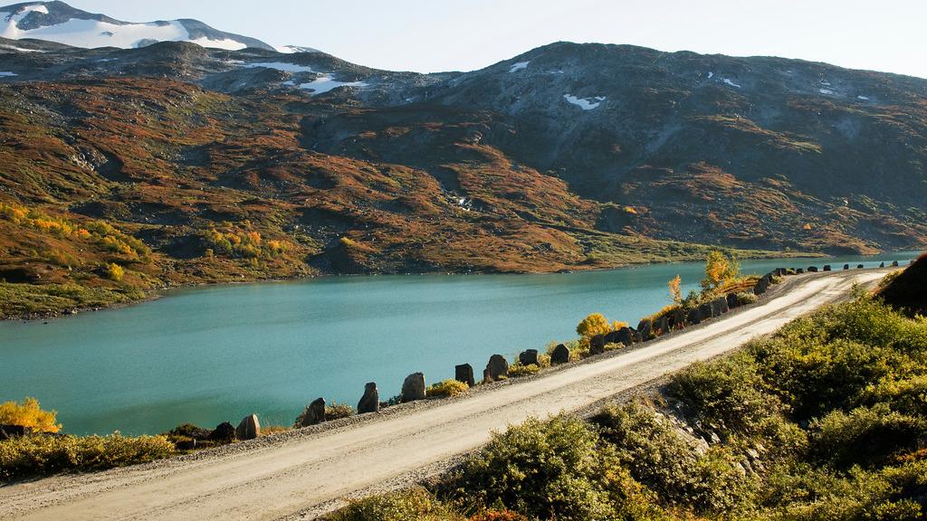 A road right next to a bright blue lake.
