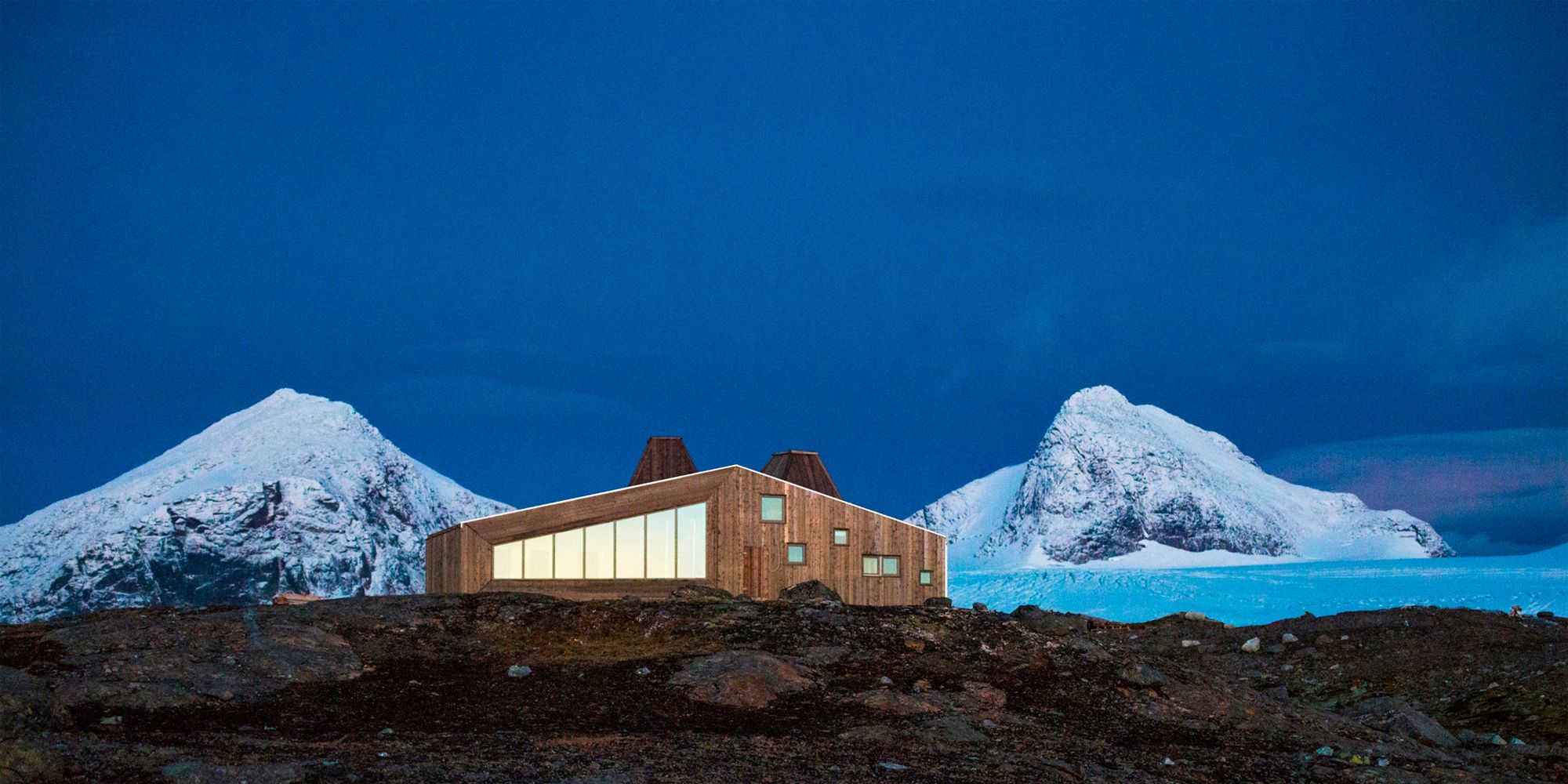 Rabothytta på Helgeland i Nord-Norge med snødekte fjell i bakgrunnen