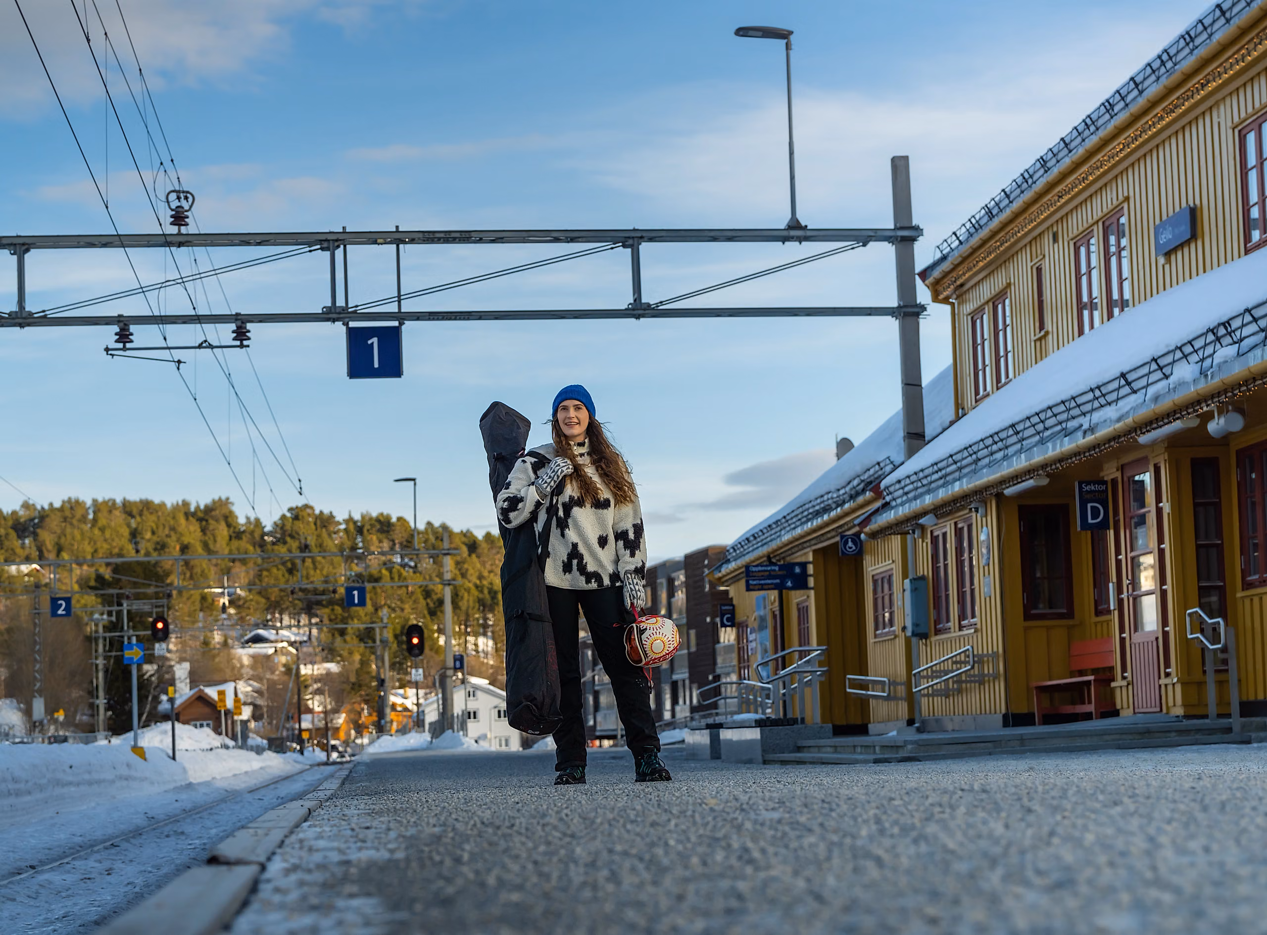 Woman in ski attire waiting on the railway platform for her train to the slopes