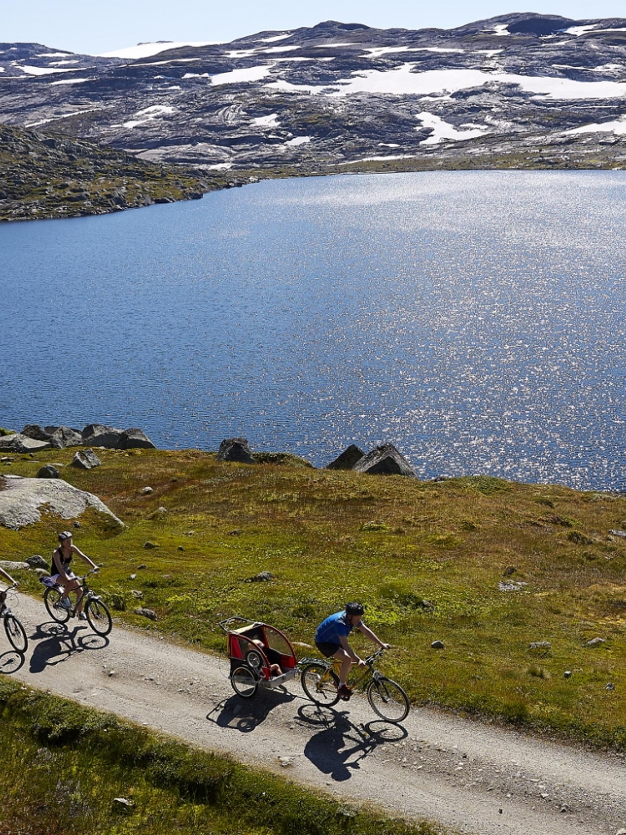 Een groep aan het fietsen over de Rallarvegen langs een meer in Oost-Noorwegen