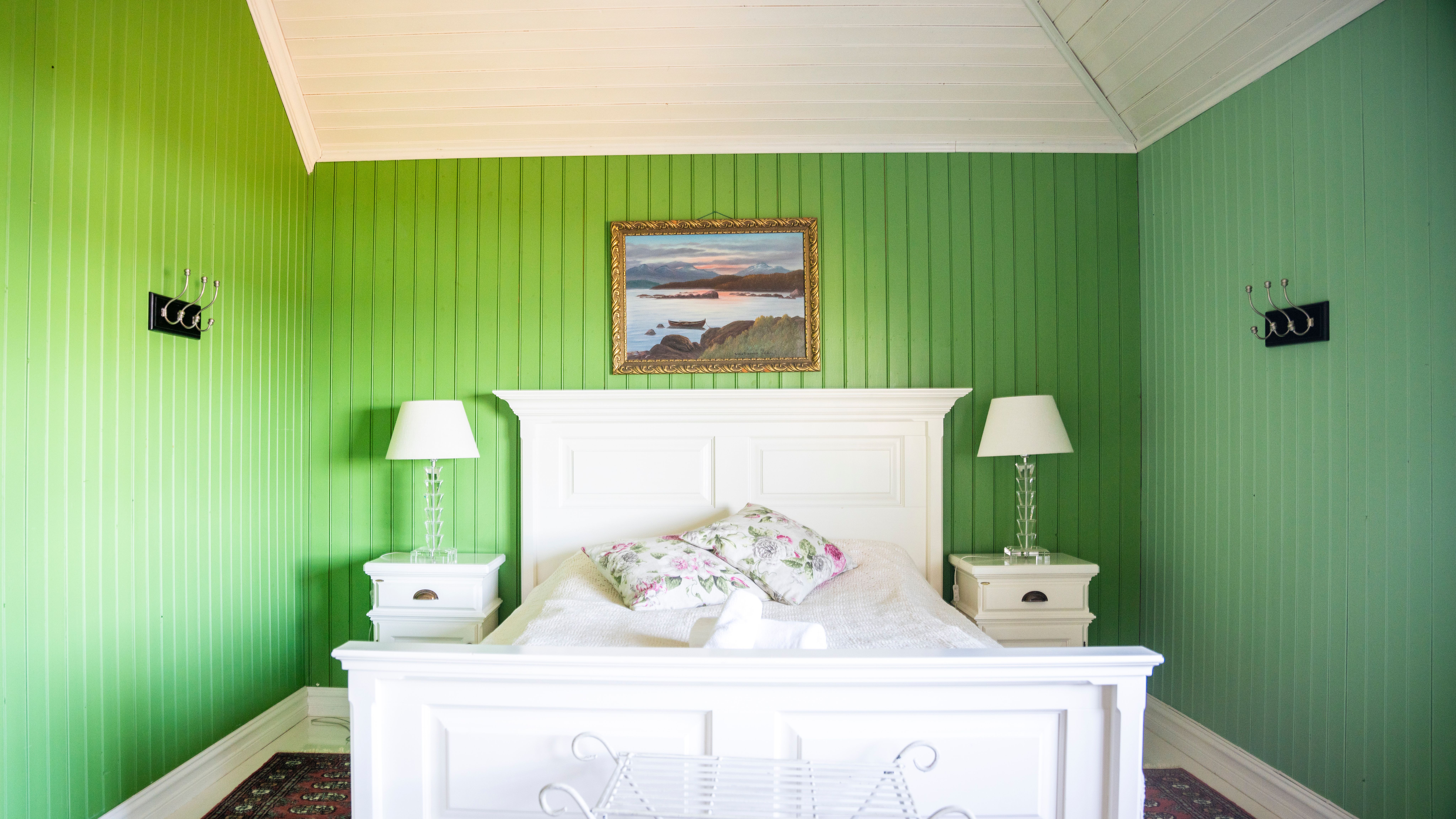 White bed in green hotel room.