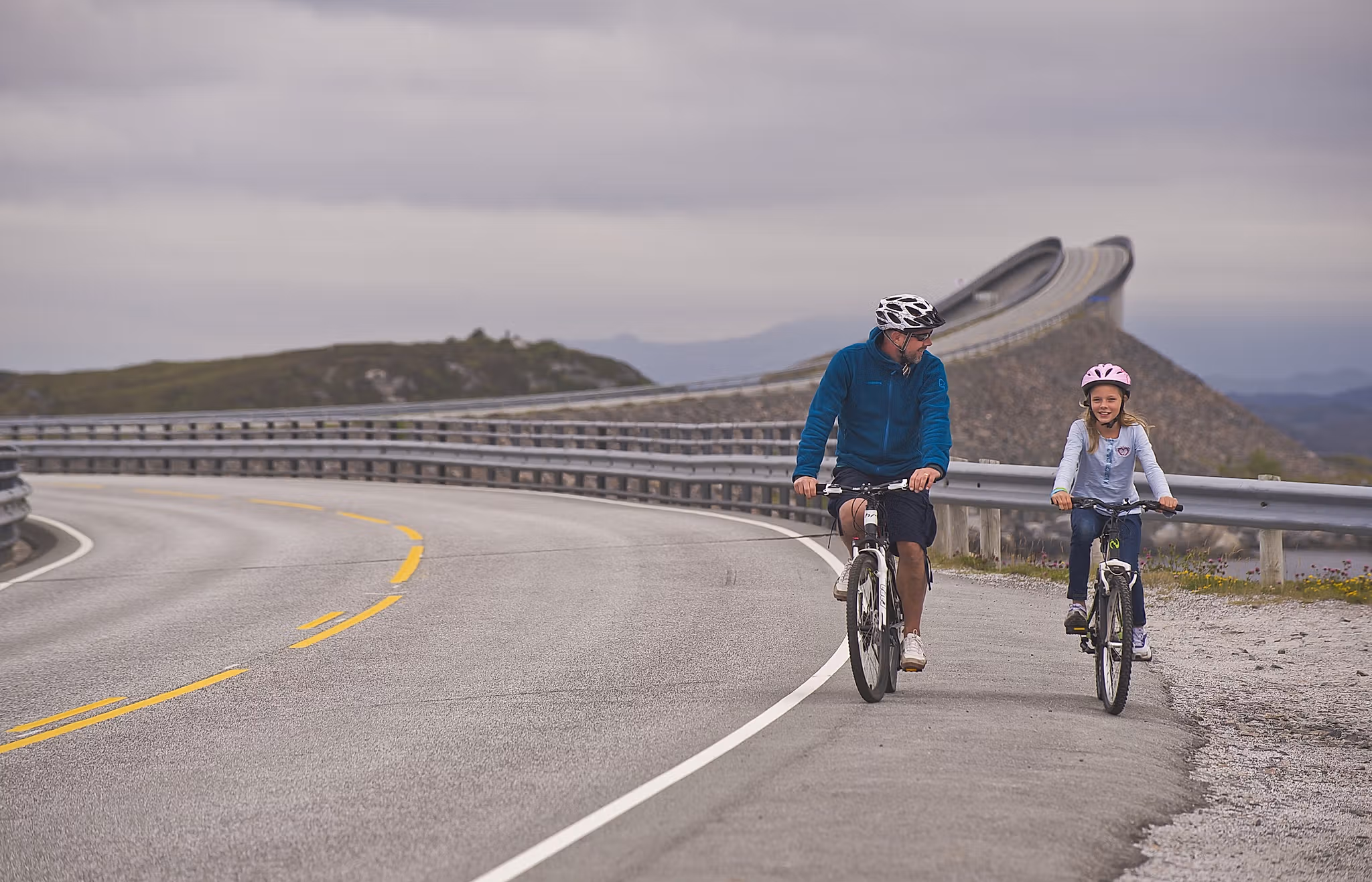 Father and daughter cycling on The Atlantic Road in the Northwest, Fjord Norway