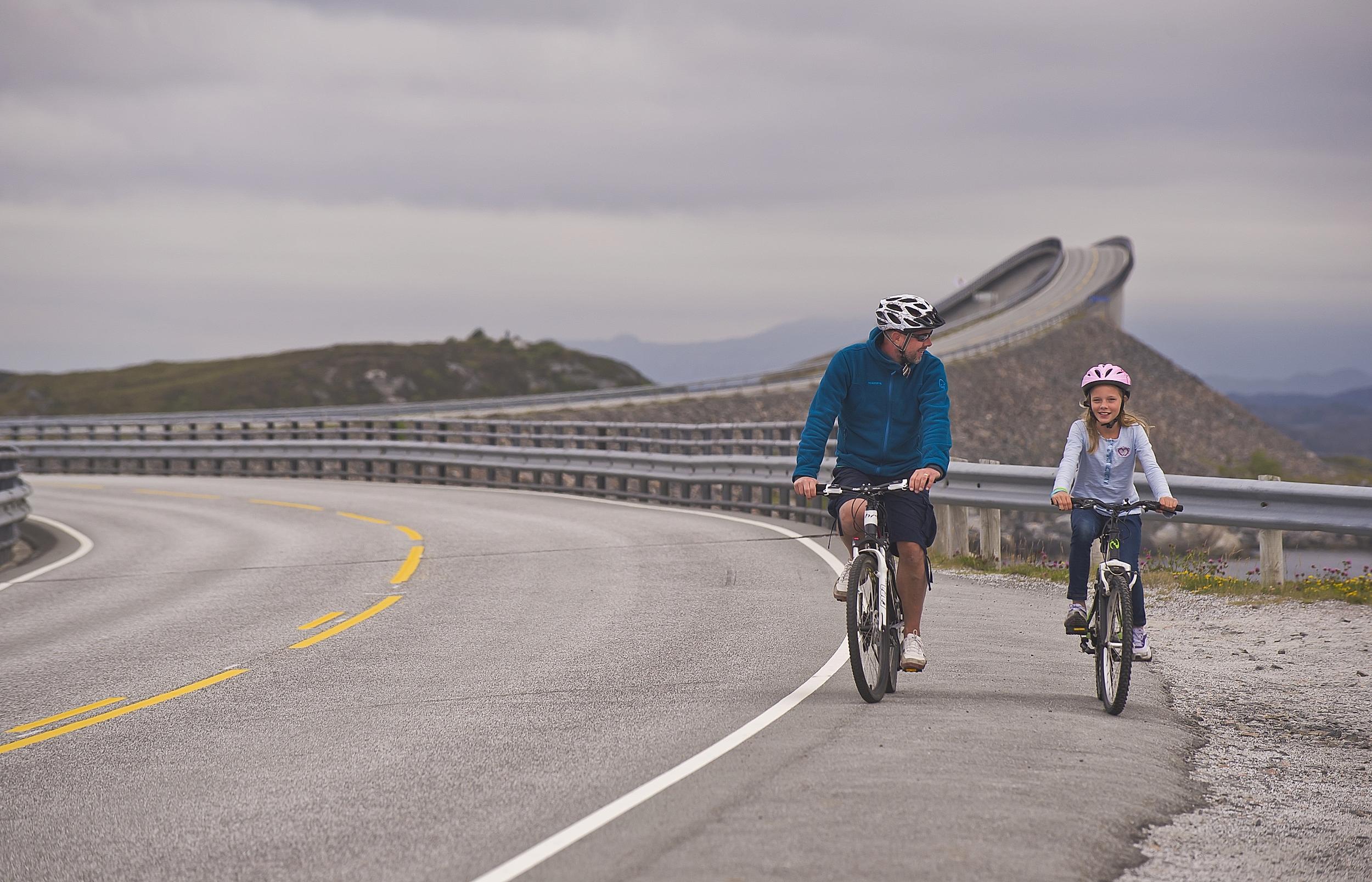 Vater und Tochter radeln auf der Atlantikstraße im Nordwesten, Fjord Norwegen