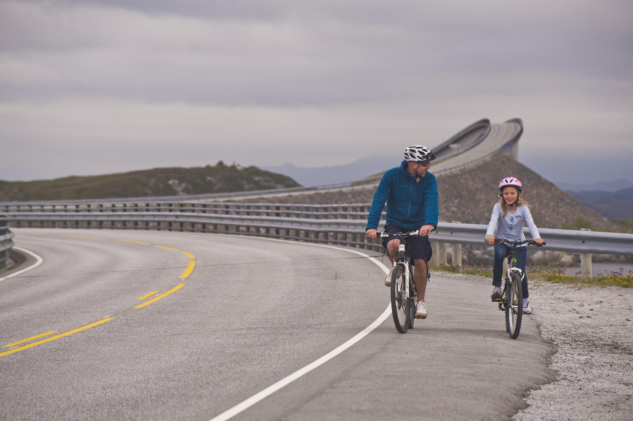 Father and daughter cycling on The Atlantic Road in the Northwest, Fjord Norway