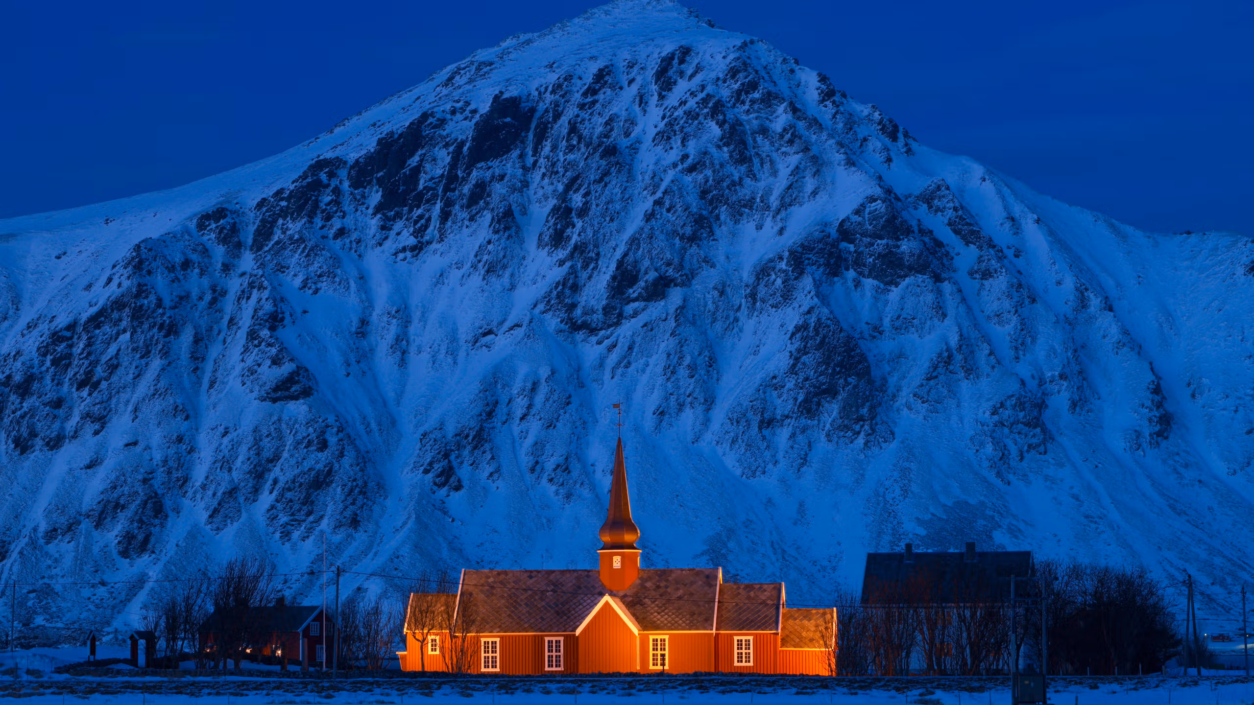 A lit up church in front of a steep mountain.